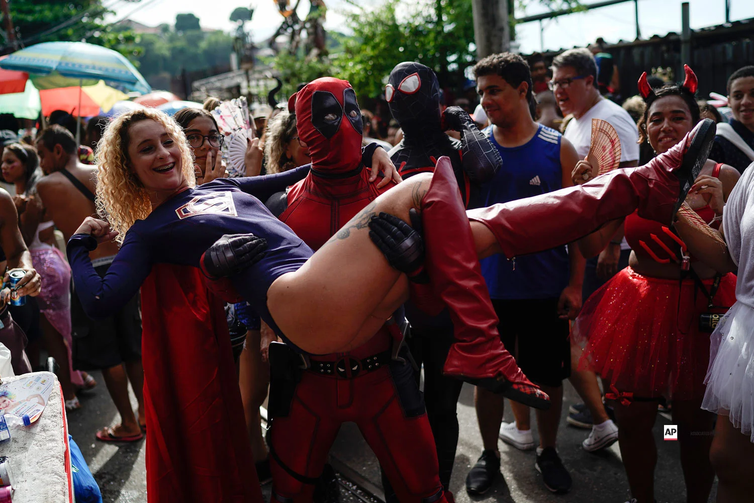 A reveler wearing a Deadpool costume carries a woman in a Super Woman costume as they enjoy the Carmelitas street party in Rio de Janeiro, Brazil, Friday, March 1, 2019. (AP Photo/Leo Correa)