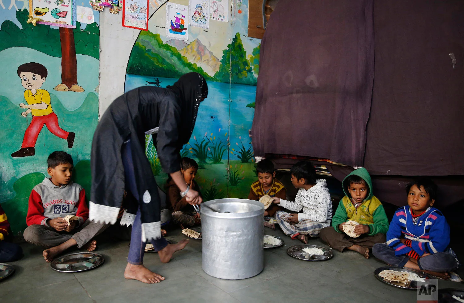 7-year-old Farmaan, second from right, waits to be served lunch meals at Salaam Baalak Trust, an NGO working for street children, in New Delhi, India on Jan. 31, 2019. (AP Photo/Altaf Qadri)