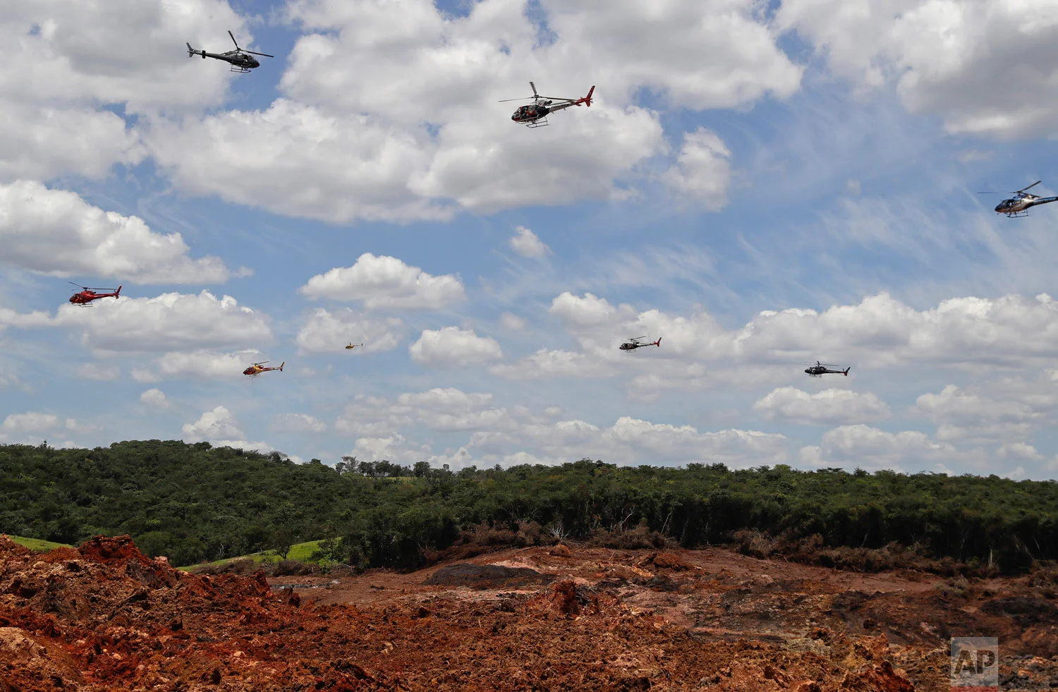 Helicopters hover over an iron ore mining complex to release thousands of flower petals paying homage to the dozens of victims killed and scores of missing after a mining dam collapsed there, in Brumadinho, Brazil, Feb. 1, 2019. (AP Photo/Andre Penner)