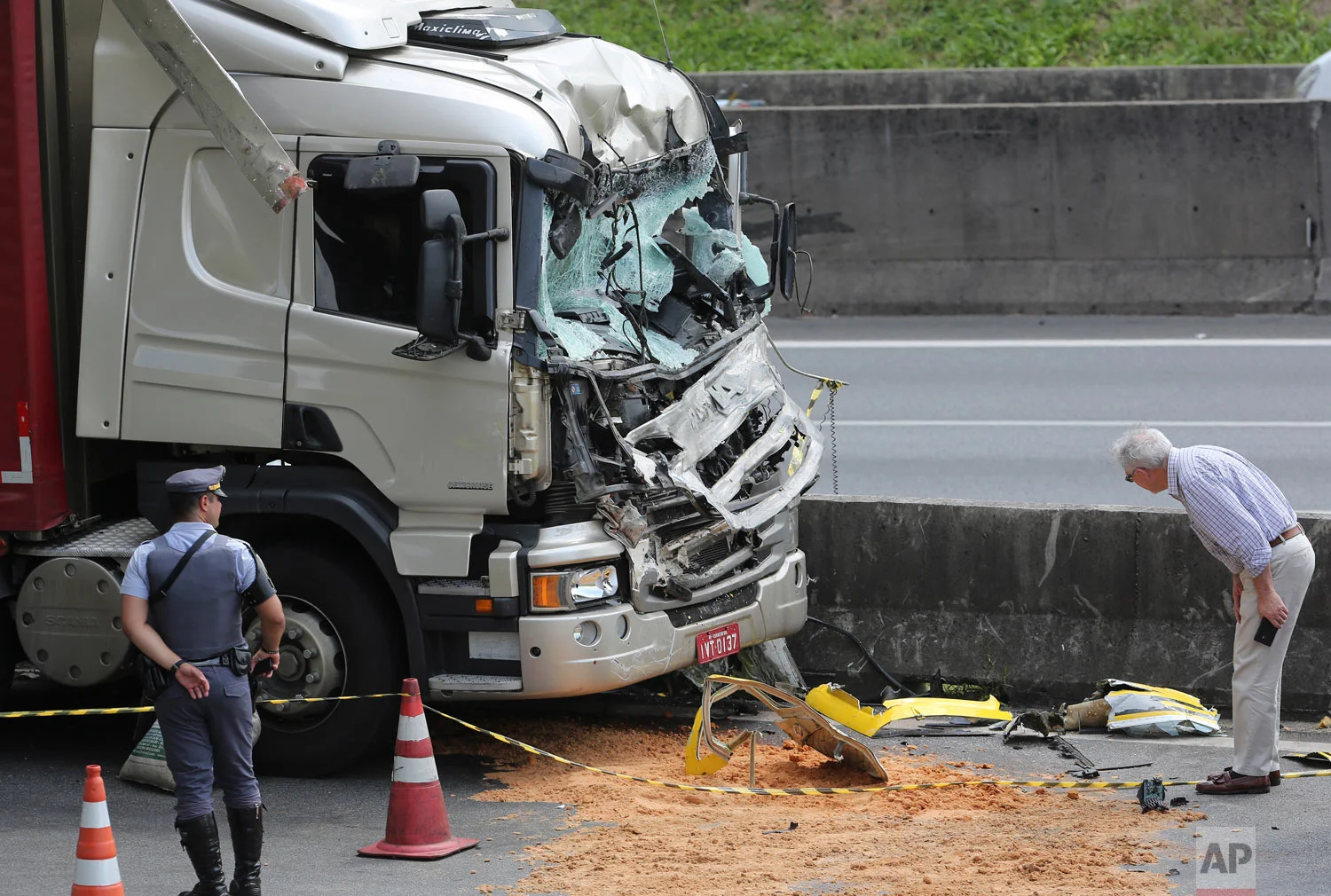 A man looks at wreckage from a helicopter where it crashed into the front of a cargo truck during an emergency landing, on a main highway in Sao Paulo, Brazil, Feb. 11, 2019. 66-year-old Brazilian television news anchor Ricardo Boechat and the pilot perished in the accident. (AP Photo/Andre Penner)