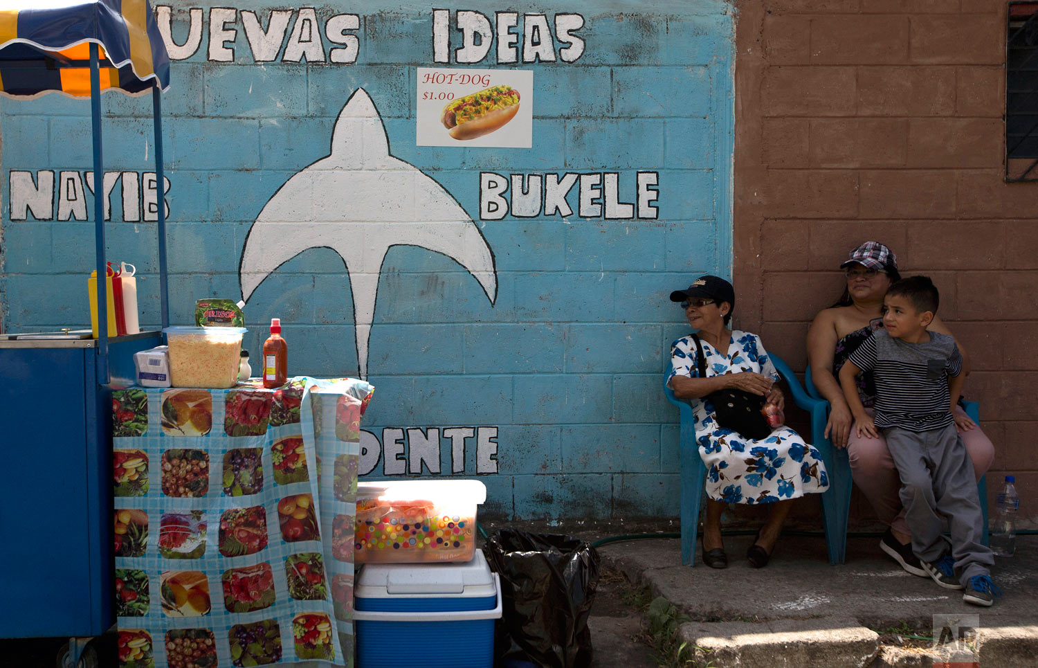 Neighbors sits next to a campaign mural promoting presidential frontrunner Nayib Bukele, of the Grand National Alliance for Unity, on the outskirts of San Salvador, El Salvador, Feb. 1, 2019. Bukele, a young businessman and former mayor of El Salvador's capital, was elected as El Salvador’s new president. (AP Photo/Moises Castillo