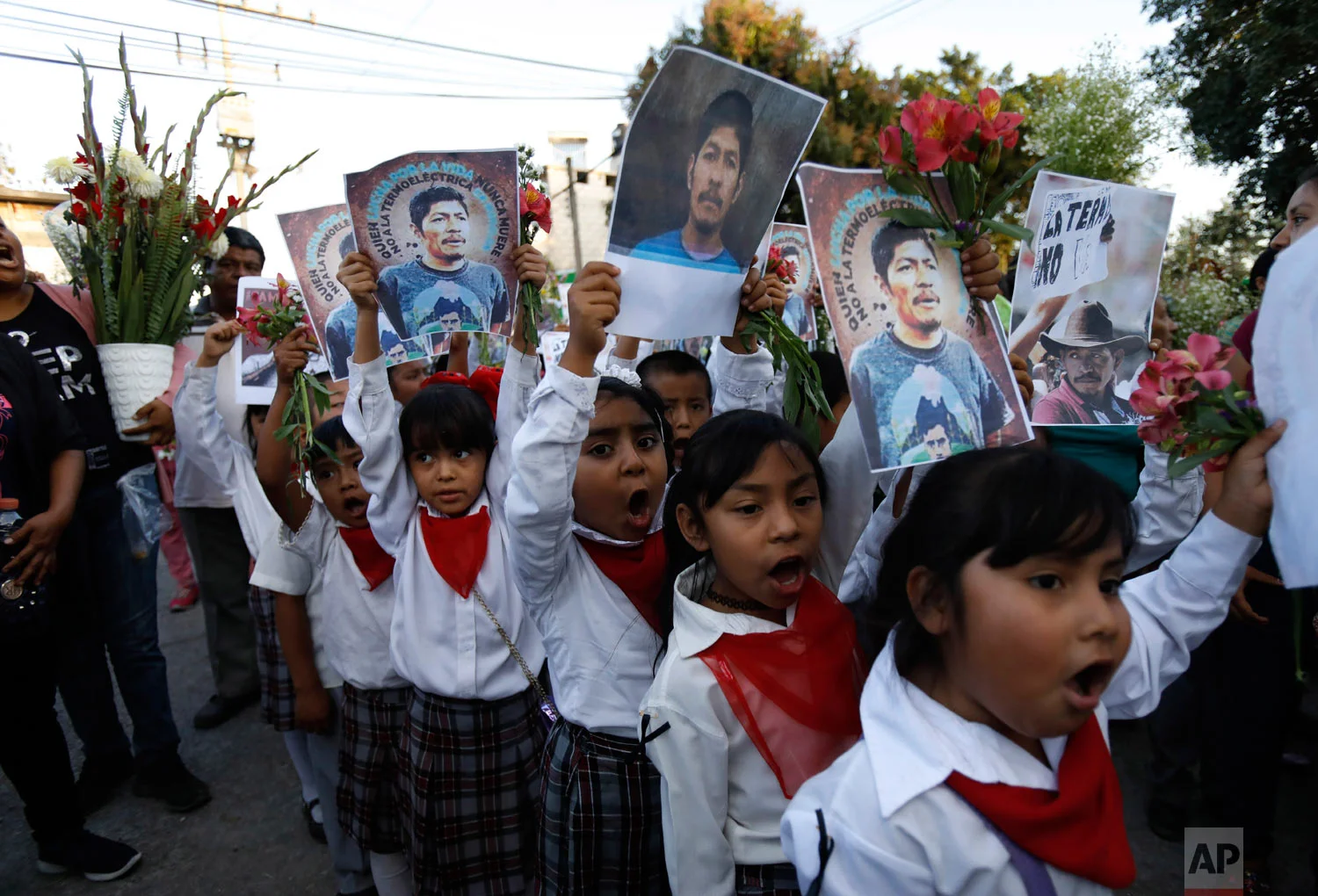  Children carry pictures of murdered community activist Samir Flores Soberanes as they accompany the coffin that contains his remains, in Amilcingo, Mexico, Feb. 21, 2019. (AP Photo/Rebecca Blackwell) 