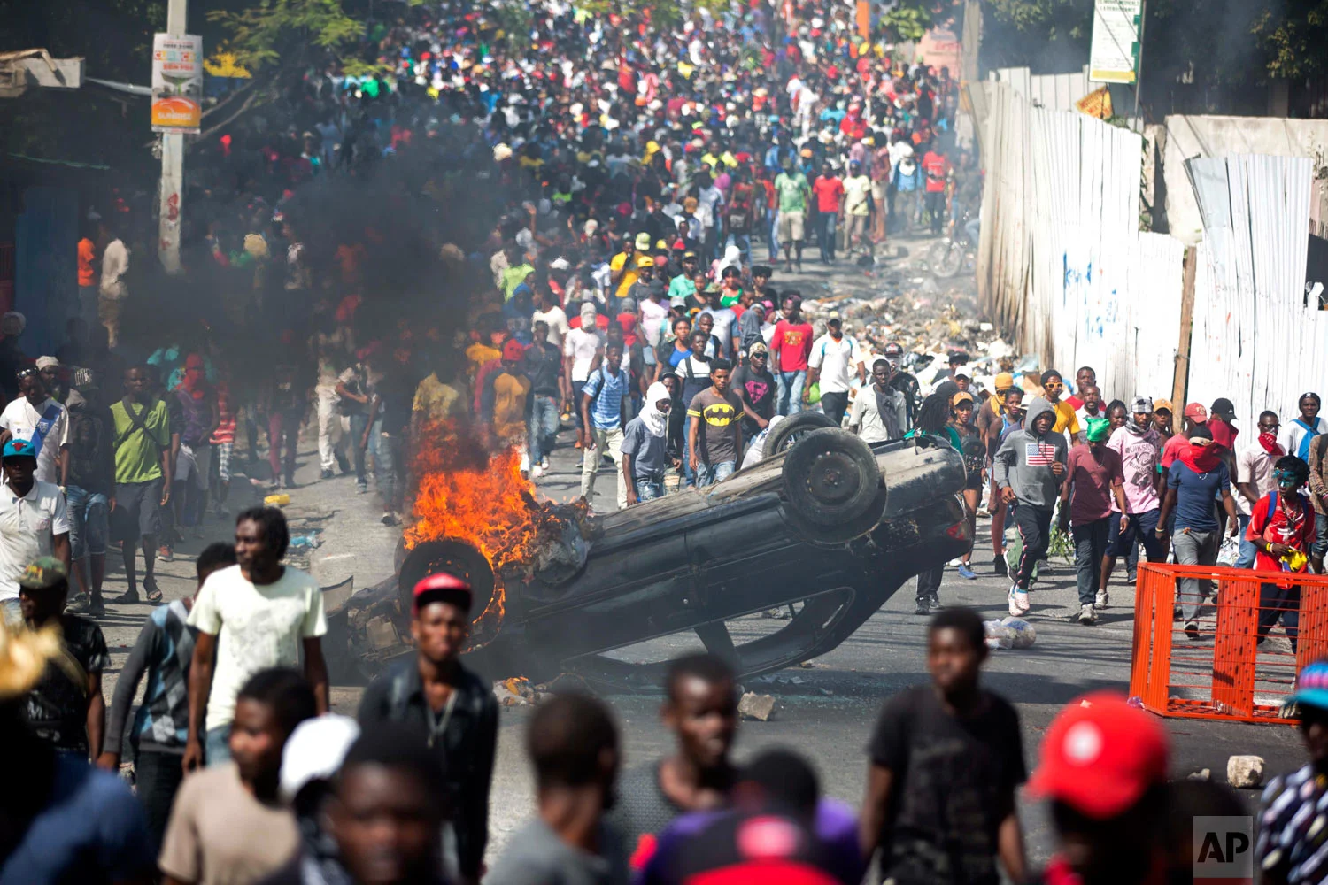  Protesters march past an overturned burning car, as they demand the resignation of Haitian President Jovenel Moise in Port-au-Prince, Haiti, Feb. 12, 2019. (AP Photo/Dieu Nalio Chery) 