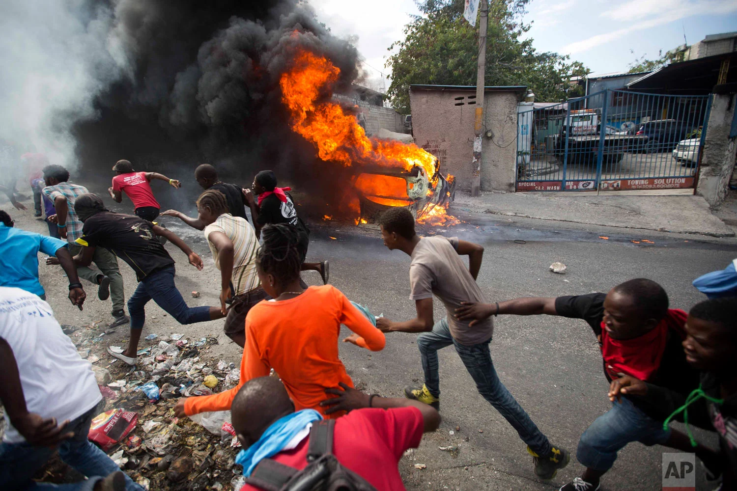  Demonstrators run from police who are shooting in their direction, as a car burns during a protest demanding the resignation of Haitian President Jovenel Moise in Port-au-Prince, Haiti, Feb. 12, 2019. (AP Photo/Dieu Nalio Chery) 