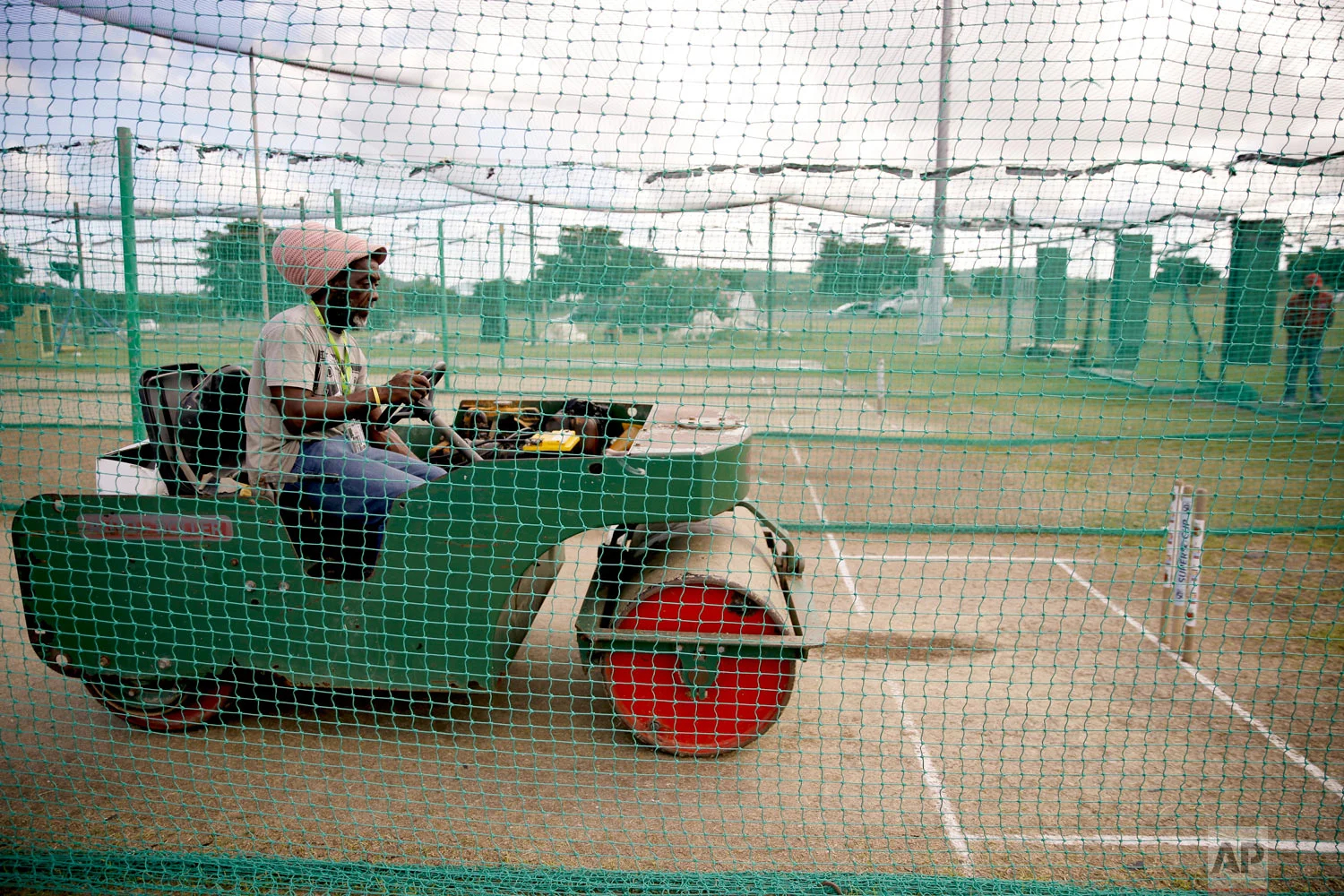 A groundskeeper rolls the pitch at the nets prior to a training session of the England cricket team at the Sir Vivian Richards stadium in North Sound, Antigua and Barbuda, Feb. 4, 2019. (AP Photo/Ricardo Mazalan)