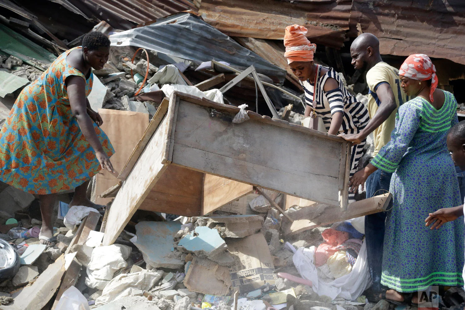 Local people look through debris at the scene after a building collapsed in Lagos, Nigeria, Thursday, March 14, 2019. (AP Photo/Sunday Alamba)