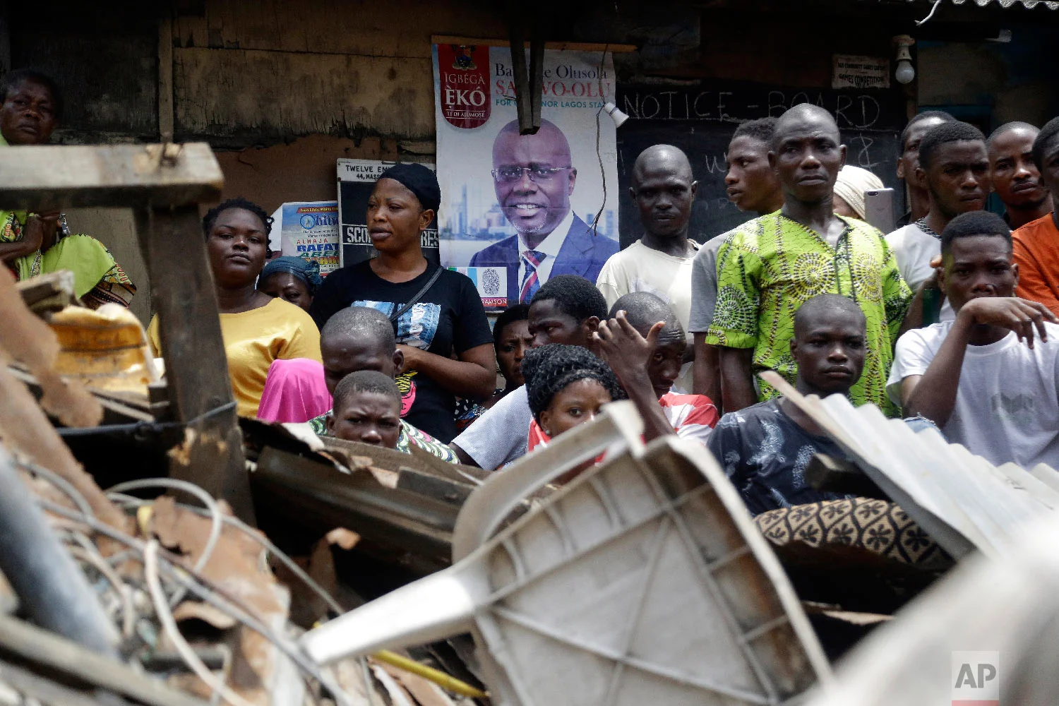 Onlookers stand at the scene of a collapsed building in Lagos, Nigeria, Thursday, March 14, 2019. (AP Photo/Sunday Alamba)