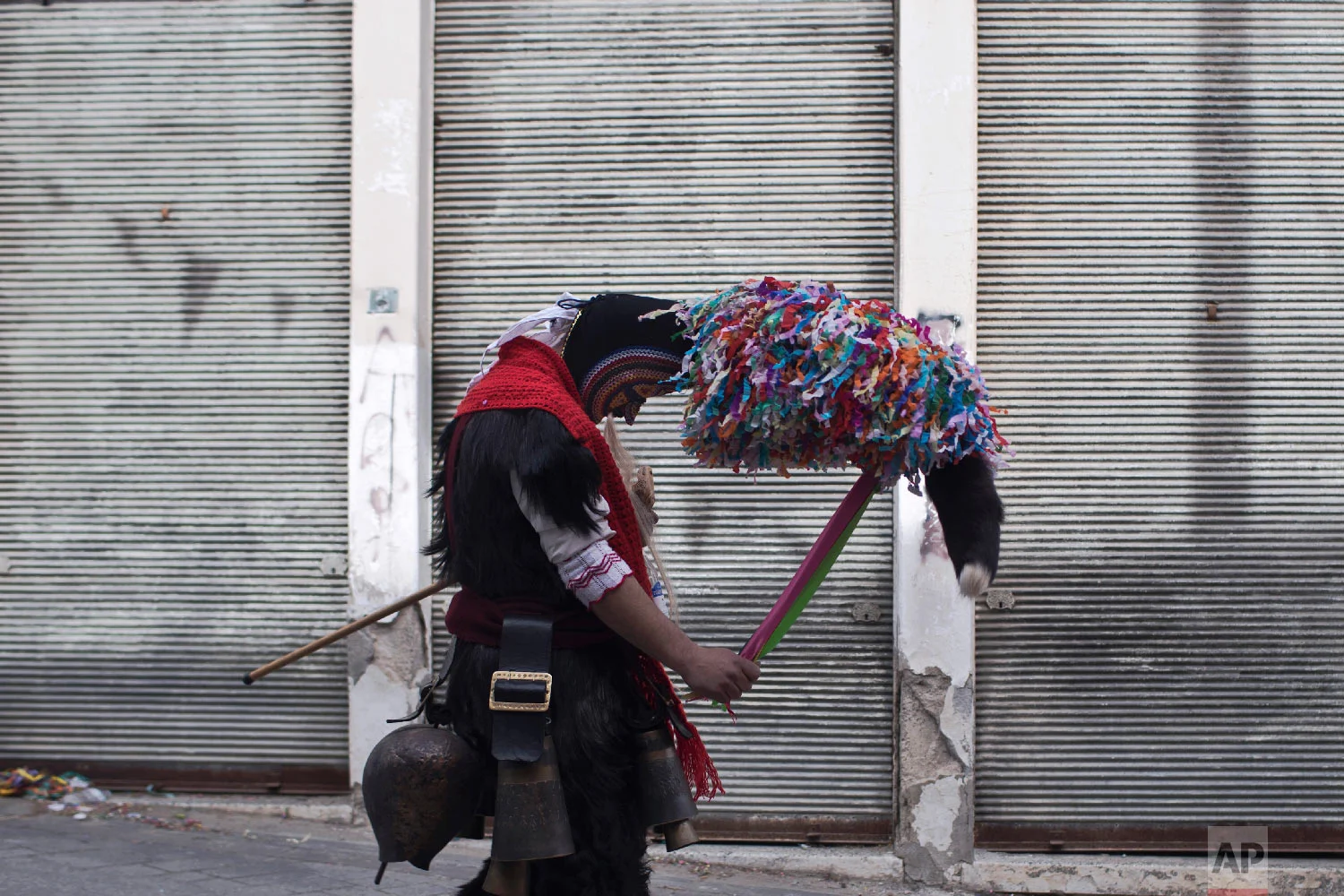 A man wearing a goat hide with bells around his waist and a mask that include a meter tall, ribbon-covered formation topped with a foxtail, also known as bell wearer, participates in a Clean Monday festival at the village of Sohos, northern Greece on March 11, 2019. (AP Photo/Petros Giannakouris)