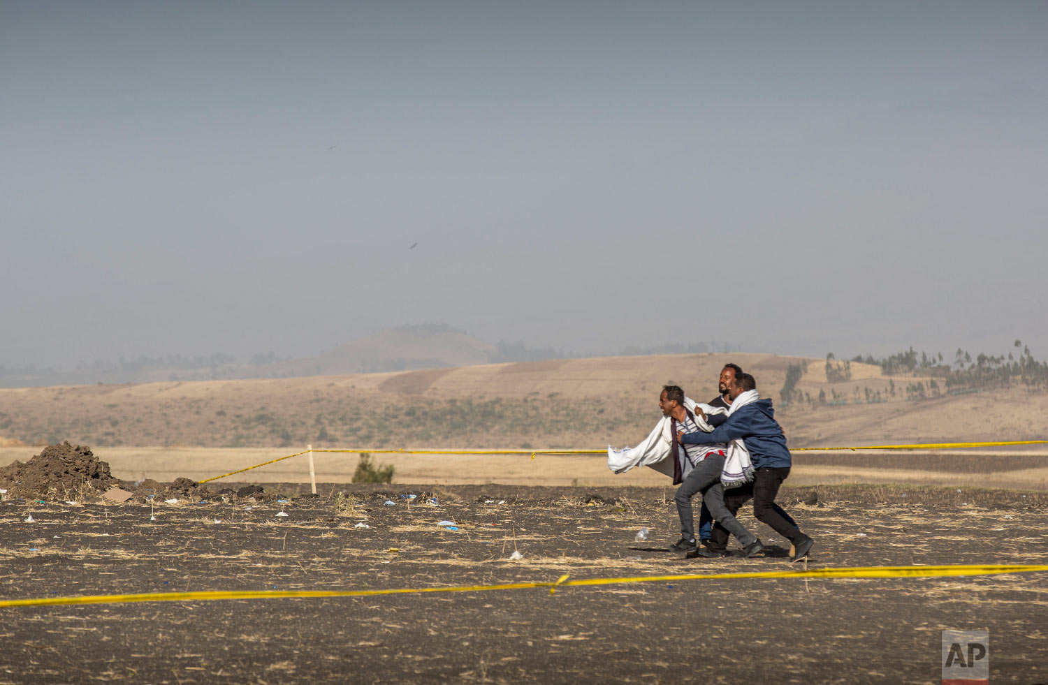 A grieving relative is held back by others at the scene where the Ethiopian Airlines Boeing 737 Max 8 crashed shortly after takeoff on Sunday near Bishoftu, Ethiopia, March 13, 2019. (AP Photo/Mulugeta Ayene)