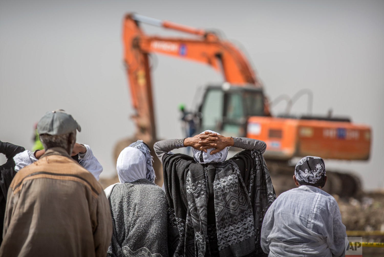 Ethiopian relatives of crash victims mourn as a mechanical digger operates at the scene where the Ethiopian Airlines Boeing 737 Max 8 crashed shortly after takeoff on Sunday near Bishoftu, Ethiopia, March 14, 2019. (AP Photo/Mulugeta Ayene)