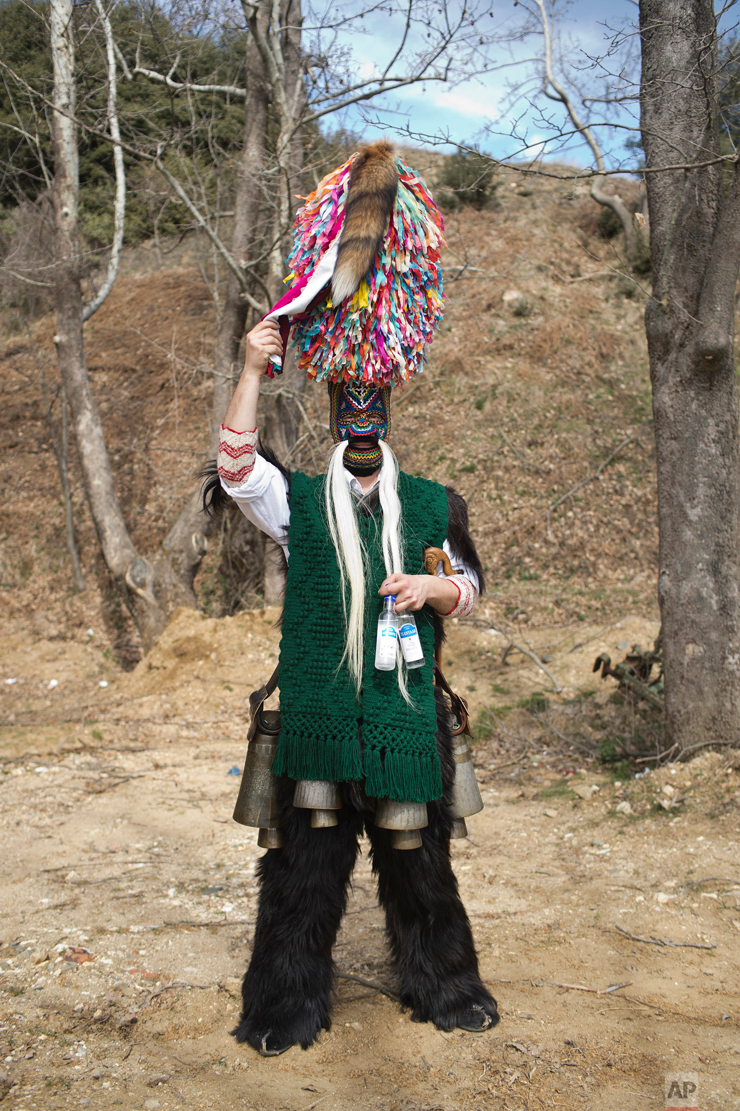  In this Monday March 11, 2019 a man wearing goat hide with bells around his waist and a mask that include a meter tall, ribbon-covered formation topped with a foxtail, also called bell wearer, poses for a picture in the village of Sohos, northern Gr