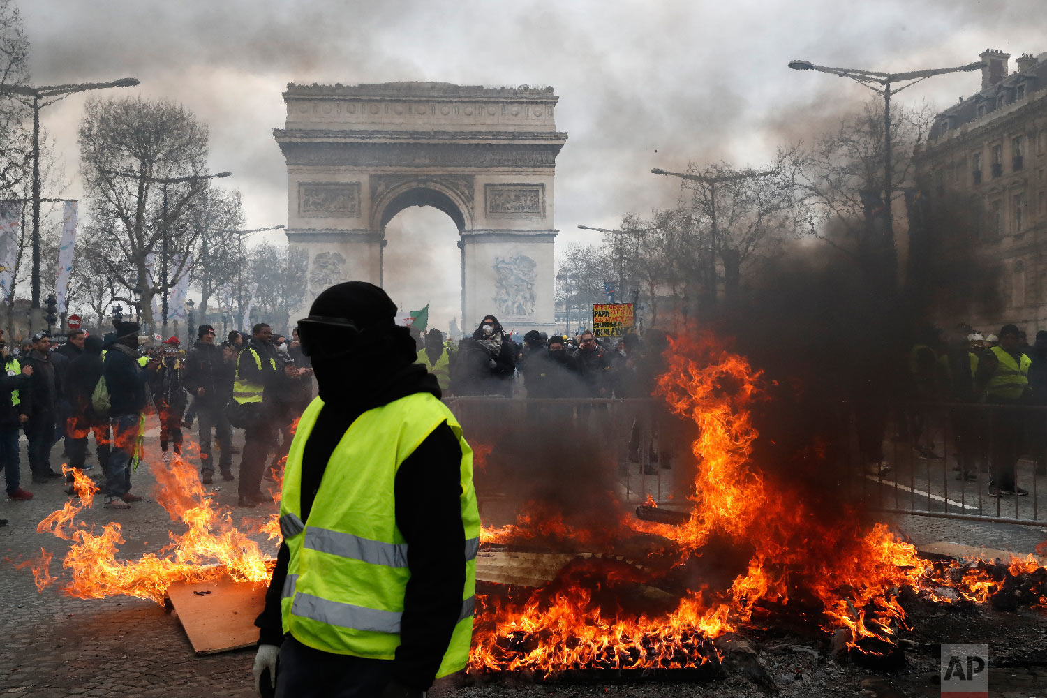 A yellow vest protester walks past a fire on the Champs Elysees avenue March 16, 2019, in Paris. (AP Photo/Christophe Ena)