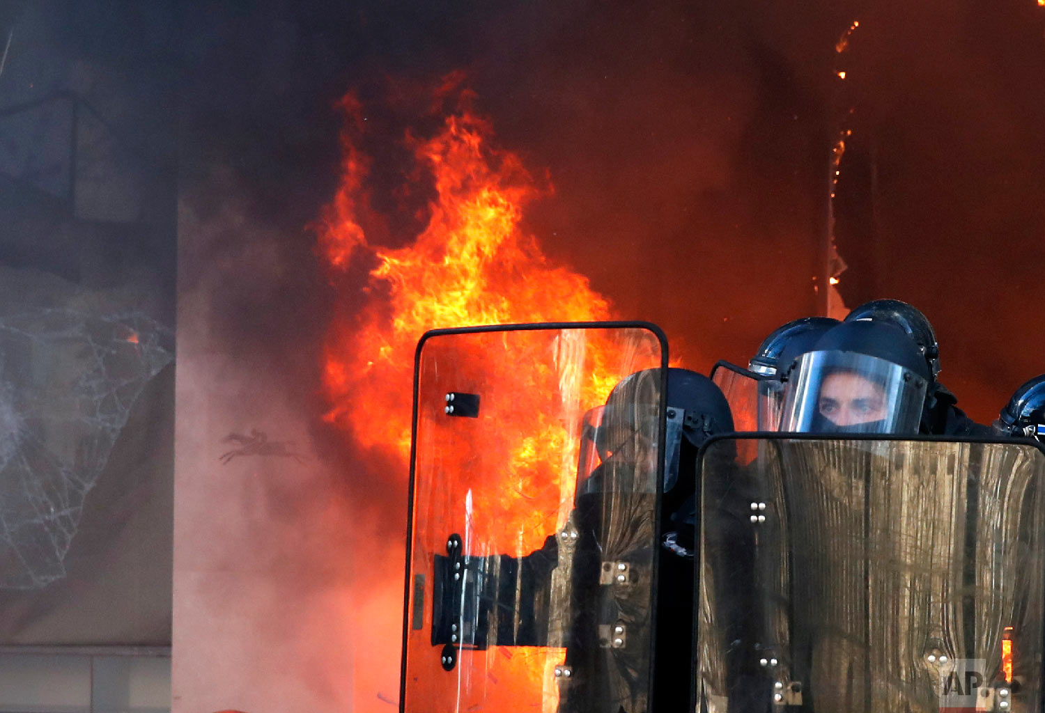 Riot police officers stand in front a burning building during a yellow vests demonstration March 16, 2019, in Paris. (AP Photo/Christophe Ena)