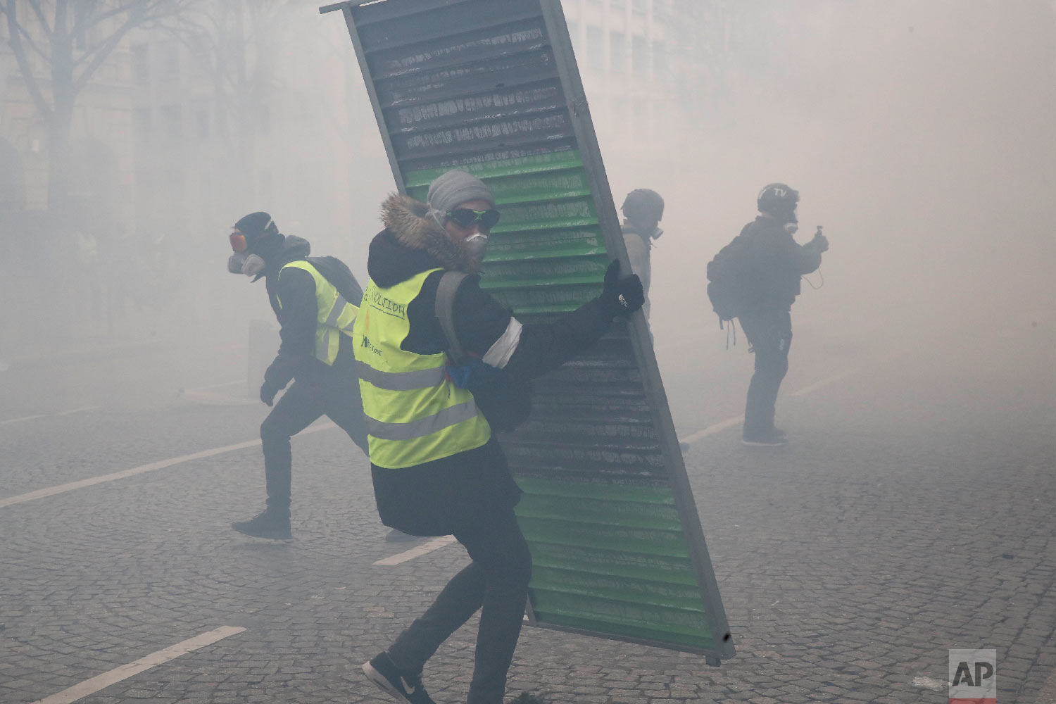 Protesters set up barricades through tear gas during a yellow vests demonstration, March 16, 2019. (AP Photo/Christophe Ena)