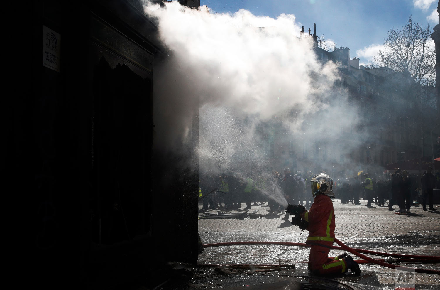 A firefighters tries to pull out a fire during a yellow vests demonstration March 16, 2019. (AP Photo/Christophe Ena)