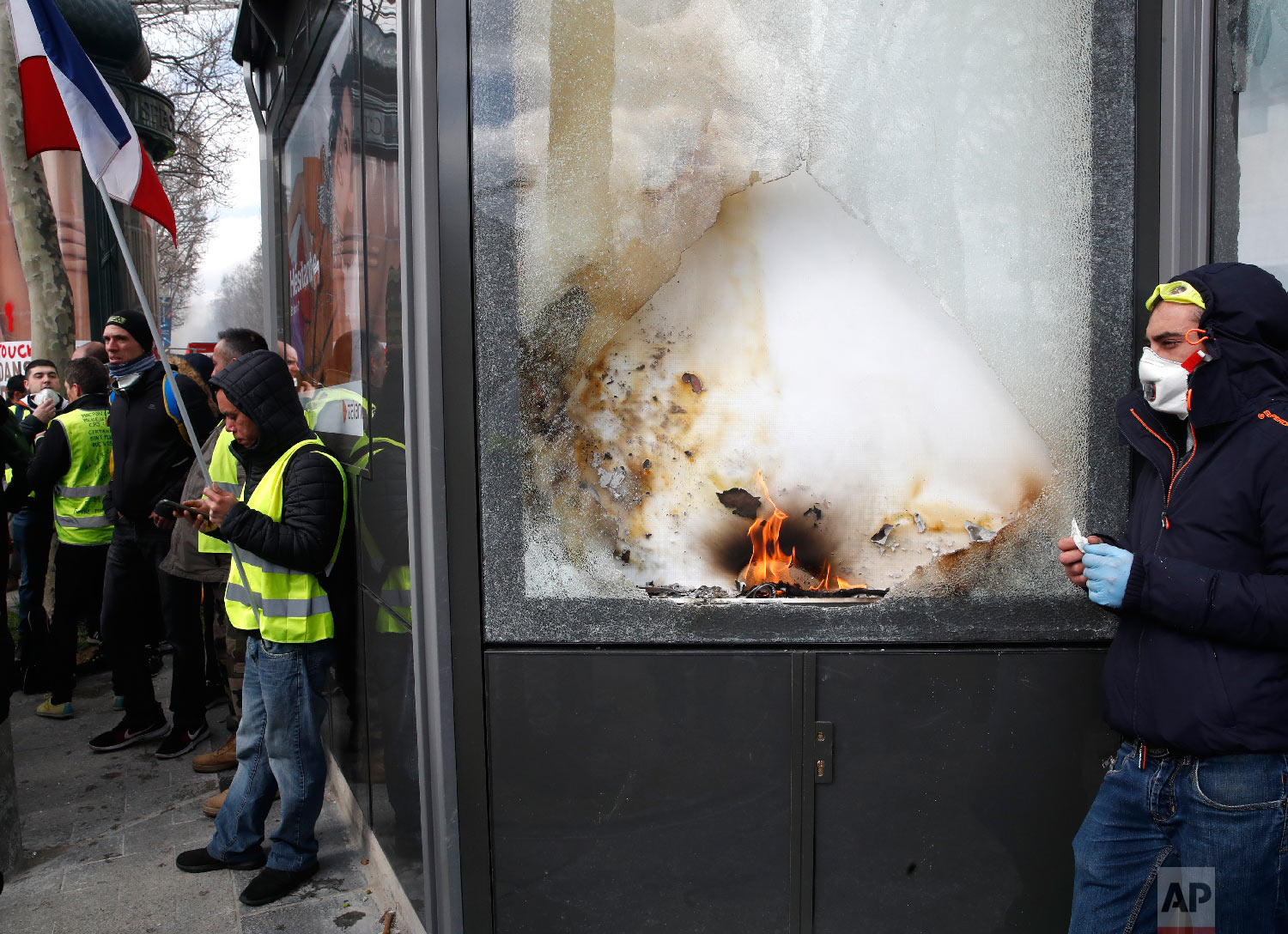 Yellow vests protesters stand by a damages shop during a demonstration, March 16, 2019. (AP Photo/Christophe Ena)