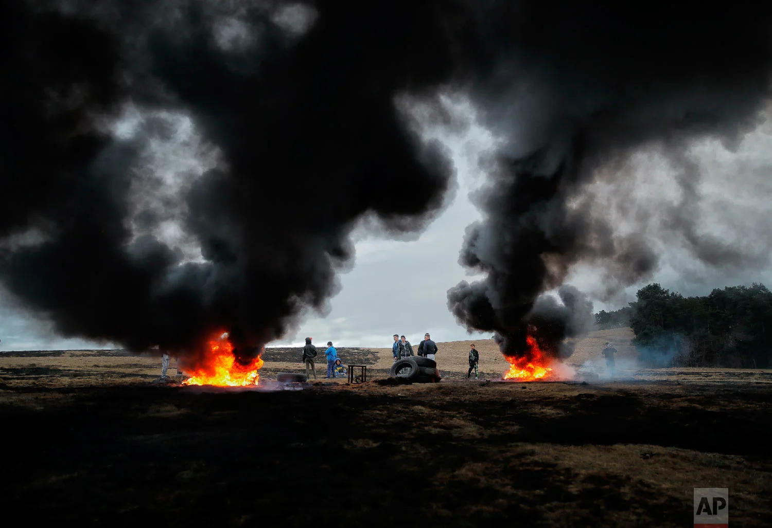 Children and youngsters stand by burning tires during a ritual marking the upcoming Clean Monday, the beginning of the Great Lent, 40 days ahead of Orthodox Easter, on the hills surrounding the village of Poplaca, in central Romania's Transylvania region, Sunday, March 10, 2019. (AP Photo/Vadim Ghirda)