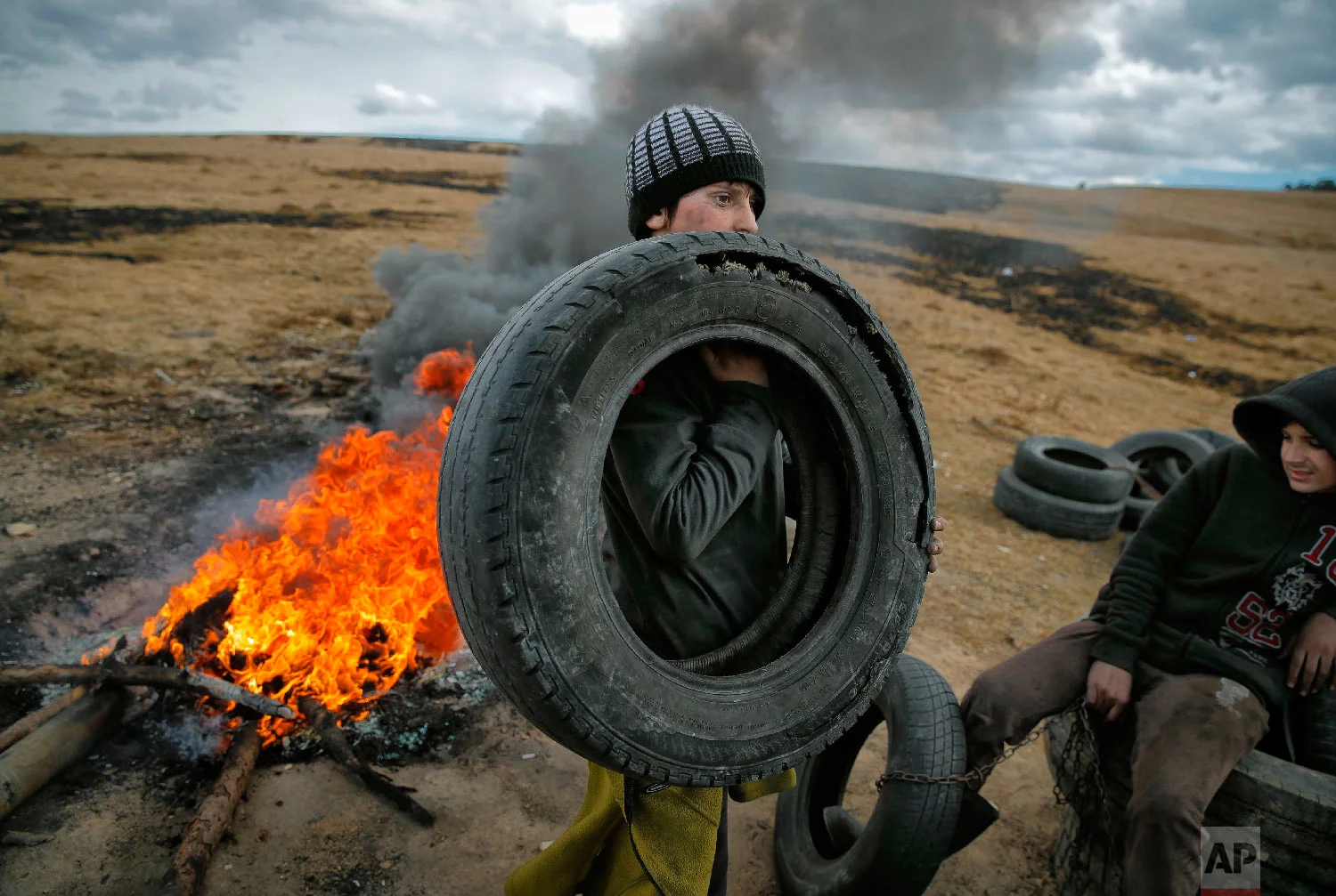 A boy handle tires during a ritual marking the upcoming Clean Monday, the beginning of the Great Lent, 40 days ahead of Orthodox Easter, on the hills surrounding the village of Poplaca, in central Romania's Transylvania region, Sunday, March 10, 2019. (AP Photo/Vadim Ghirda)