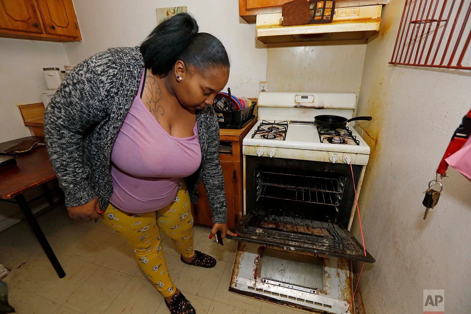 In this Feb. 20, 2019 photo, Destiny Johnson shows the broken door to her oven that she uses string to hold together, in her apartment in Cedarhurst Homes, a federally subsidized, low-income apartment complex in Natchez, Miss. The complex failed a health and safety inspection in each of the past three years. Upset with conditions, Johnson moved out in late March. (AP Photo/Rogelio V. Solis)