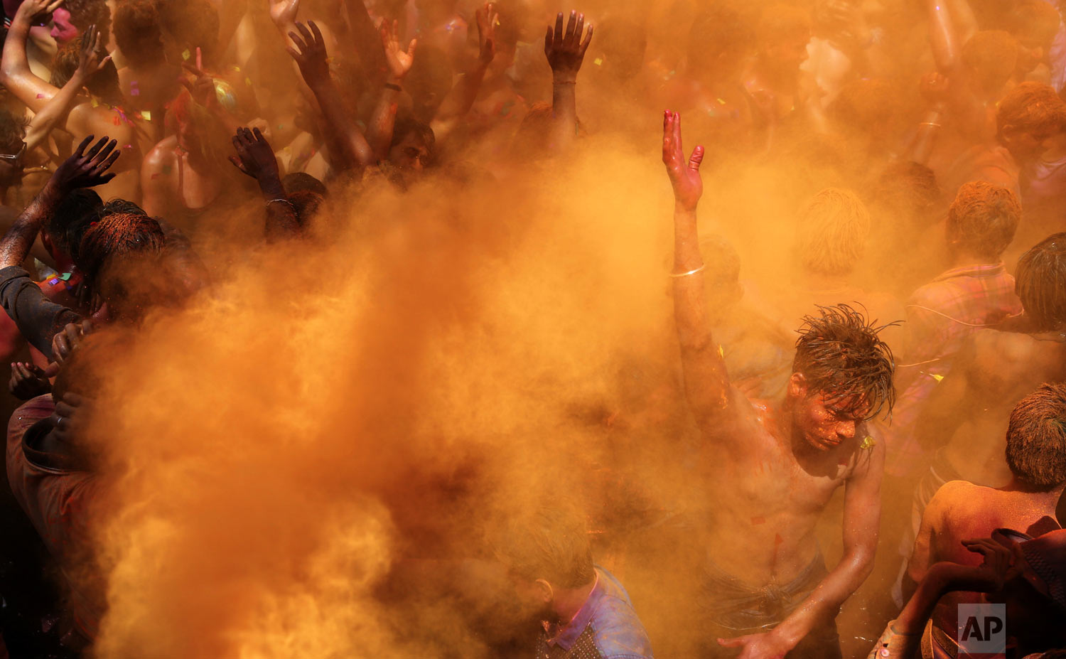 Revelers dance as colored powders are sprayed during celebrations for the Hindu festival Holi in Prayagraj, India, on Friday, March 22, 2019. The riotous annual celebration of color, marks the end of winter and the arrival of spring. People armed with water balloons, colored water and powder in multiple hues played Holi by smearing each other's faces with color. (AP Photo/ Rajesh Kumar Singh)