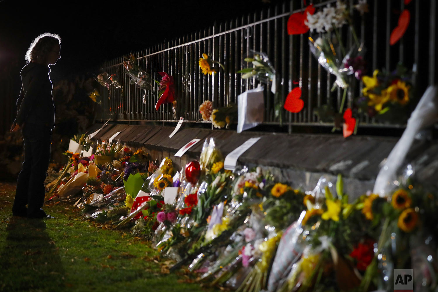 Mourners pay their respects at a makeshift memorial near the Masjid Al Noor mosque in Christchurch, New Zealand, Saturday, March 16, 2019. New Zealand's stricken residents reached out to Muslims in their neighborhoods and around the country, to show kindness to a community in pain as a 28-year-old white supremacist stood silently before a judge, accused in mass shootings at two mosques that left dozens of people dead. (AP Photo/Vincent Thian)
