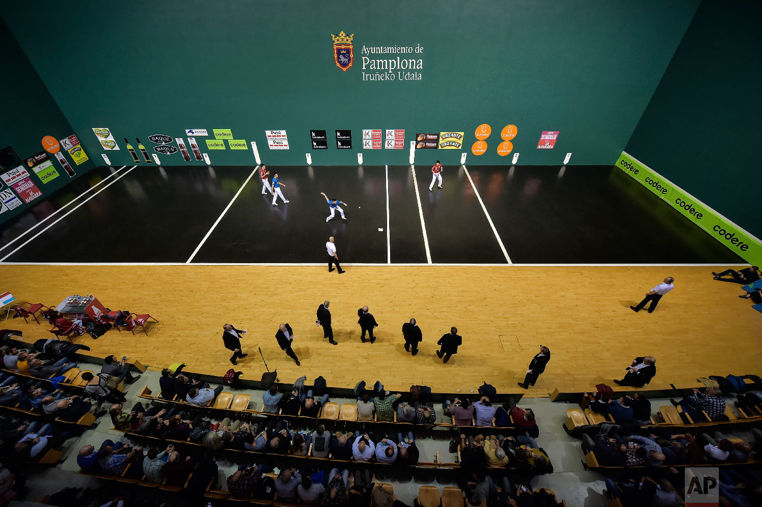 Victor Esteban, center, prepares to hit the ball with his hand during a match at Labrit court or fronton, in Pamplona, northern Spain on March 9, 2019. (AP Photo/Alvaro Barrientos)