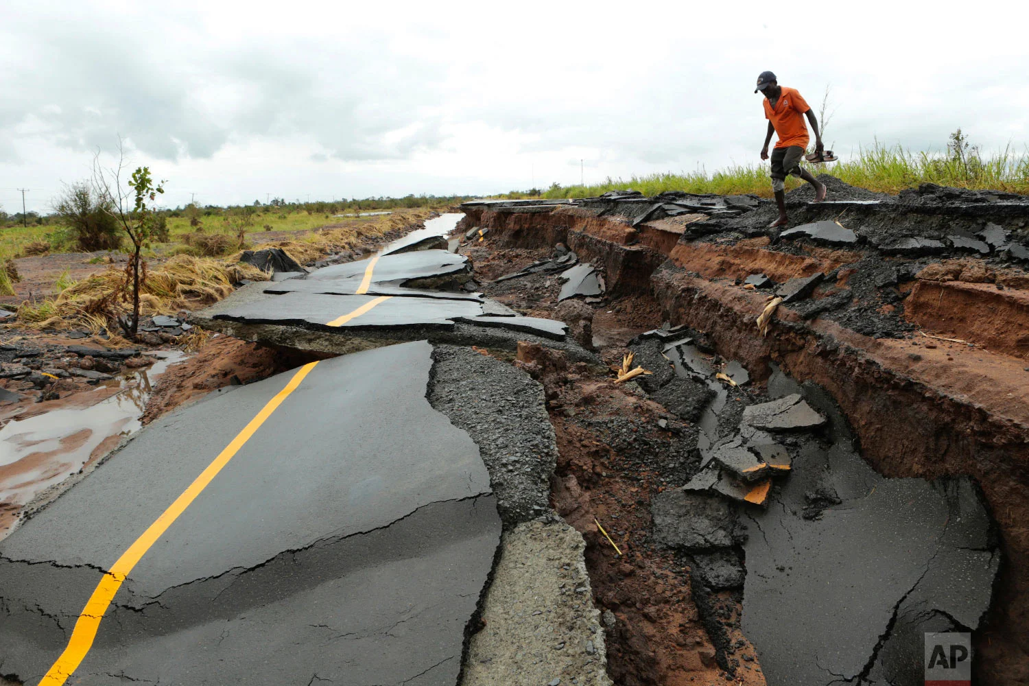 A man walks through a section of a road damaged by Cyclone Idai in Nhamatanda, Mozambique, about 50 kilometers (30 miles) from Beira, on Friday March, 22, 2019. (AP Photo/Tsvangirayi Mukwazhi)