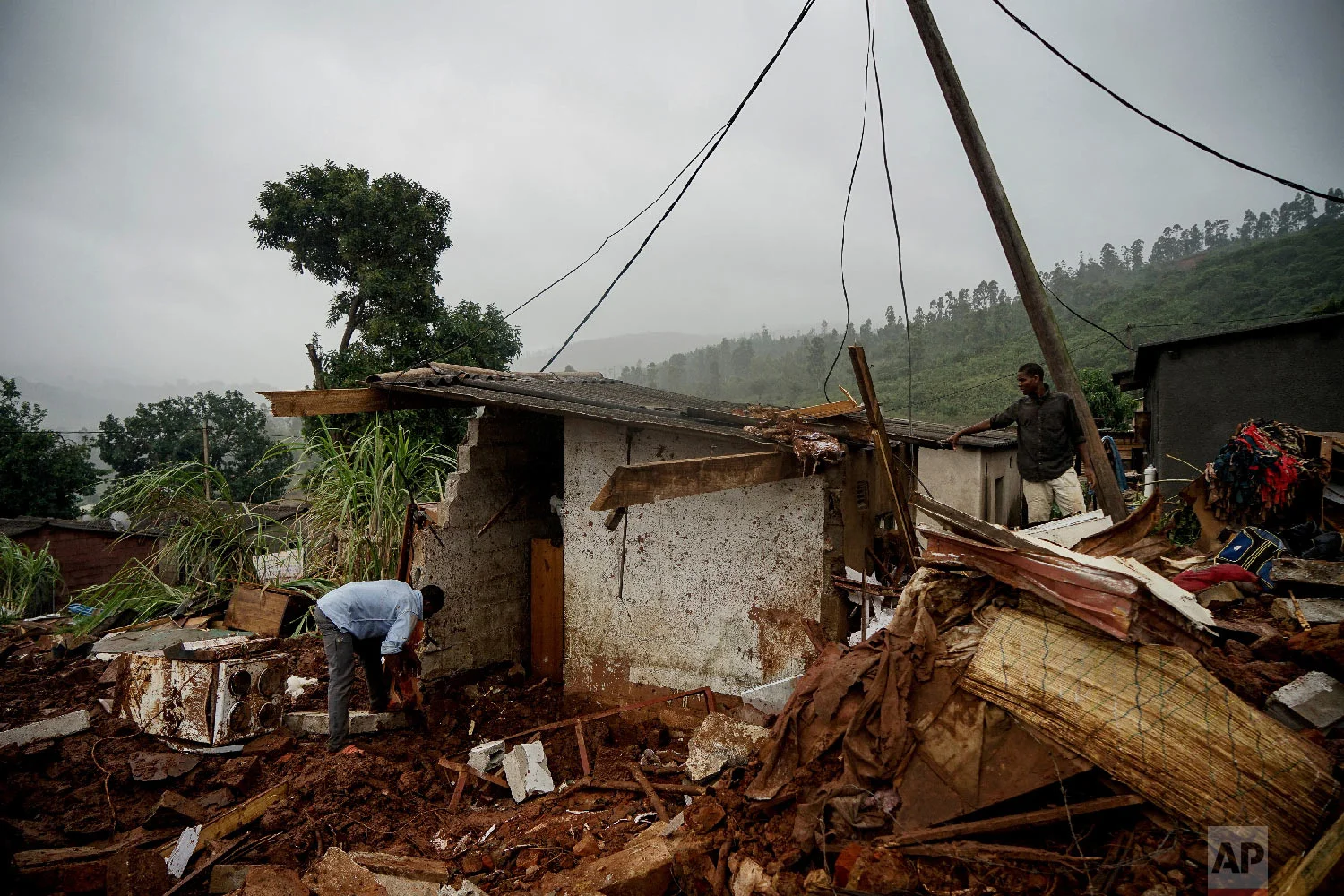 Men search to salvage what they can from a house which was damaged by Cyclone Idai in Chimanimani, Zimbabwe, Saturday, March 23, 2019 after Cyclone Idai caused floods that swept through Mozambique, Zimbabwe and Malawi. (AP Photo/KB Mpofu)