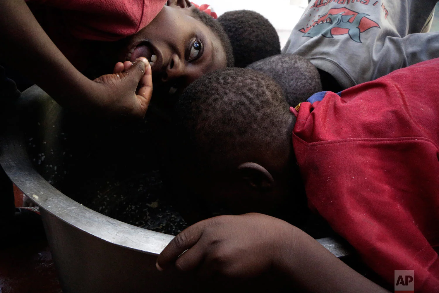 Kids scrape through for remaining rice inside a pot at a displacement centre in Beira, Mozambique, Friday, March 22, 2019. (AP Photo/Themba Hadebe)