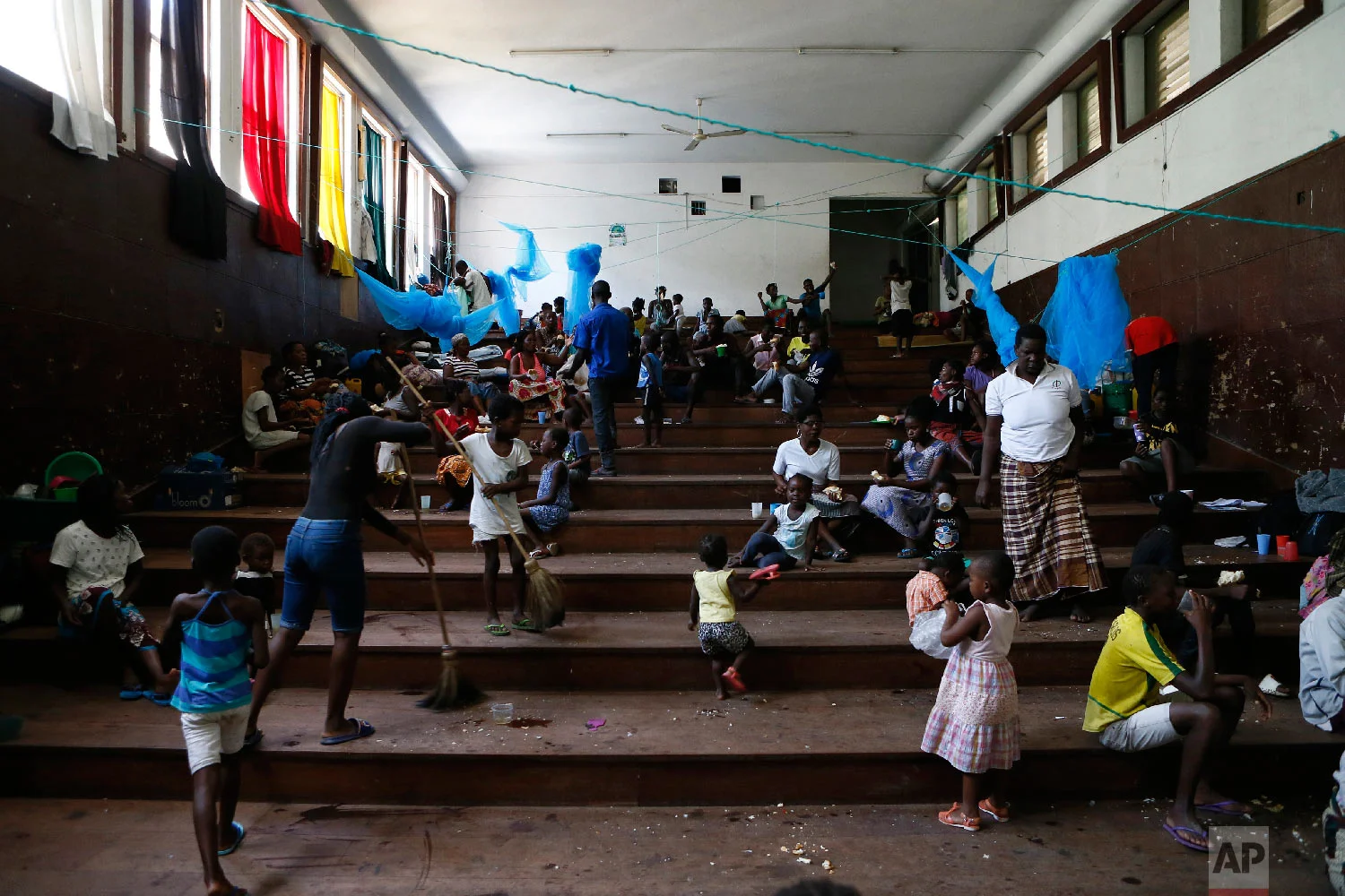 Displaced families victims of Cyclone Idai, eat lunch at the Samora Machel Secondary School which is being used to house victims of the floods in Beira, Mozambique, Sunday March 24, 2019. (AP Photo/Phill Magakoe)