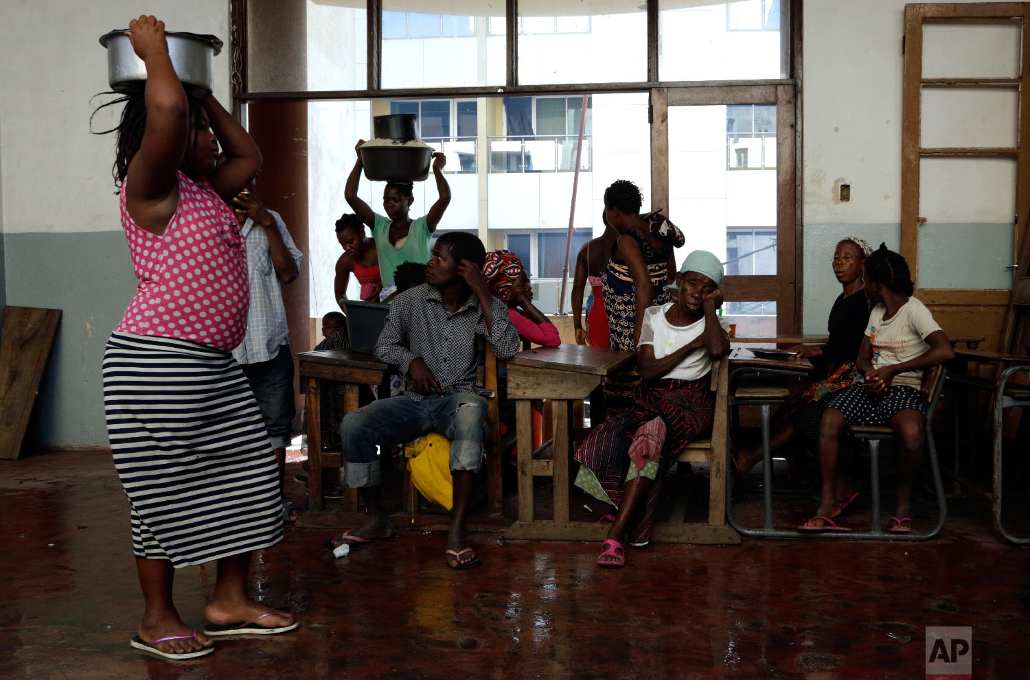 Displaced families sits on a bench at a school in Beira, Mozambique, Friday, March 22, 2019. (AP Photo/Themba Hadebe)