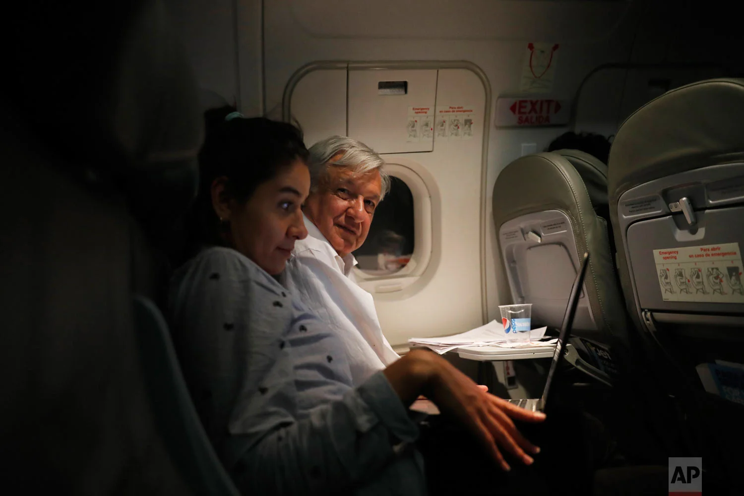 In this March 9, 2019 photo, Mexican President Andres Manuel Lopez Obrador, center, sits with an assistant as he travels in economy class aboard a commercial flight from Guadalajara to Mexico City. (AP Photo/Marco Ugarte)