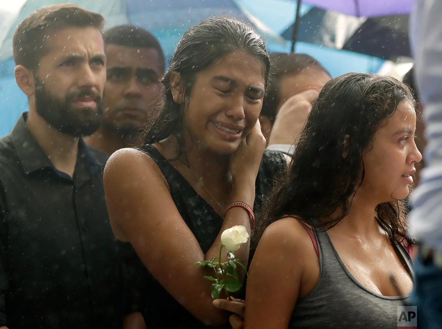 In this March 14, 2019 photo, a woman stands weeping in the rain during the burial of 15-year-old student Kaio Lucas da Costa Limeira, a victim of a mass shooting at the Raul Brasil State School in Suzano, Brazil. (AP Photo/Andre Penner)