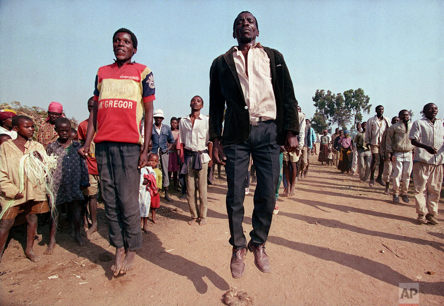 Displaced Hutu civilians in Cyanika, about 50 miles southwest of Kigali, jump in the air as part of government training of new Hutu militias in Rwanda, June 17, 1994. (AP Photo/Jean-Marc Bouju)