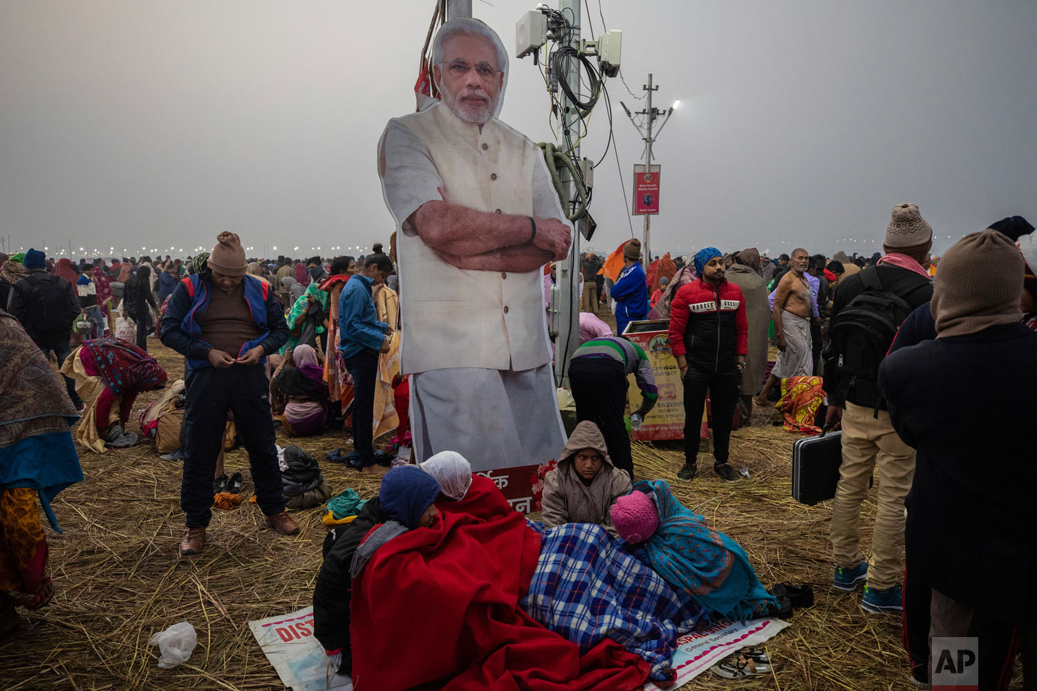 People stand near a poster of Prime Minister Narendra Modi during the Kumbh Mela festival in Allahabad, India, Jan. 14, 2018. (AP Photo/Bernat Armangue)