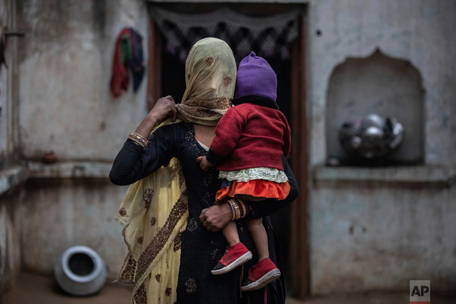 The wife of Saghir Khan, Anisa Khan, holds their daughter, Alfisa, at the family's house in Mirzapur, Jan. 22, 2019, Saghir was beaten by a group of Hindus after being spotted transporting cows. (AP Photo/Bernat Armangue)