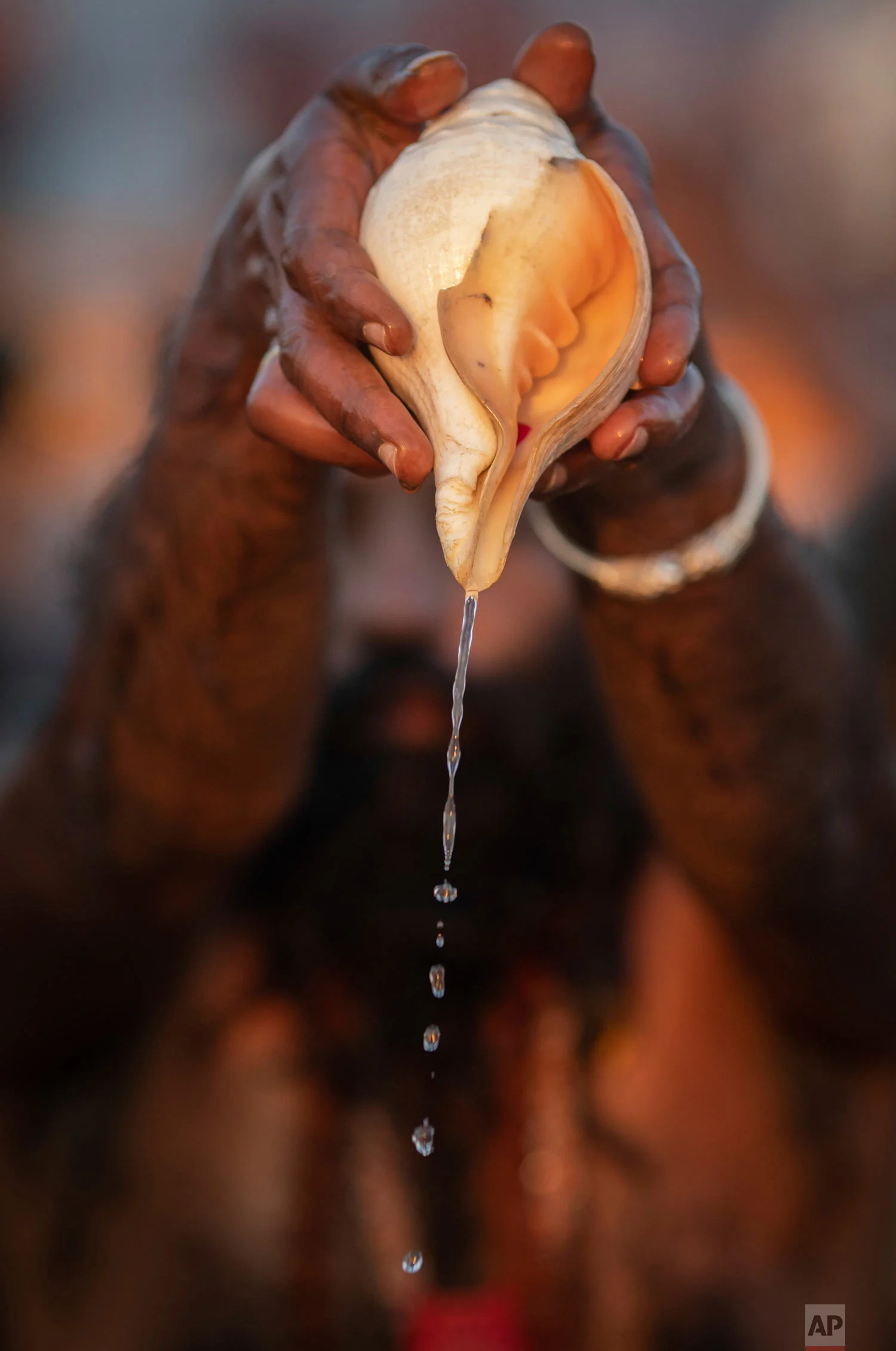 A sadhu, a Hindu holy man, pours water from a shell as he takes a ceremonial cleansing dip at Sangam, during the Kumbh Mela festival in Prayagraj, India on Jan. 15, 2019. (AP Photo/Bernat Armangue)