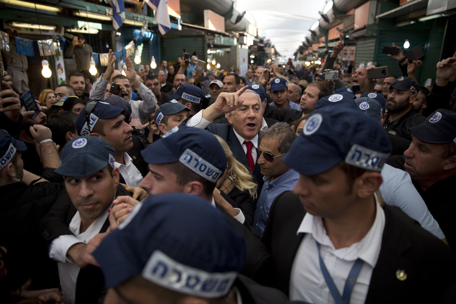 Israeli Prime Minister Benjamin Netanyahu, head of the Likud party, center, is escorted by security guards during a visit to the Ha'tikva market in Tel Aviv, Israel, Tuesday, April 2, 2019. Twitter says it has "taken action" after an Israeli watchdog exposed an alleged bot network spreading propaganda in support of Prime Minister Benjamin Netanyahu and smearing his opponents. (AP Photo/Oded Balilty)