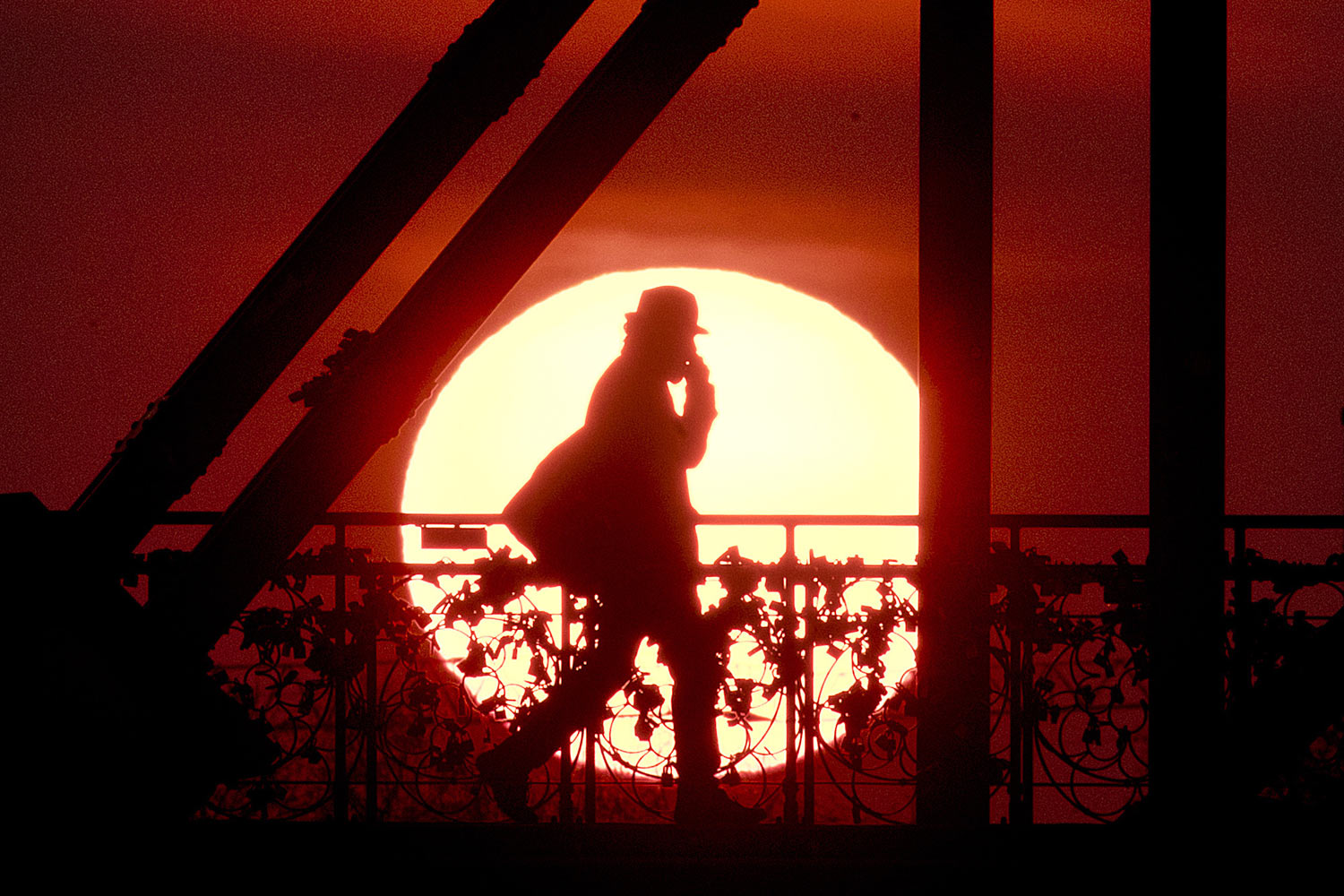 A man walks across the Eiserne Steg (Iron Footbridge) in Frankfurt, Germany, as the sun rises early Tuesday, April 2, 2019. (AP Photo/Michael Probst)