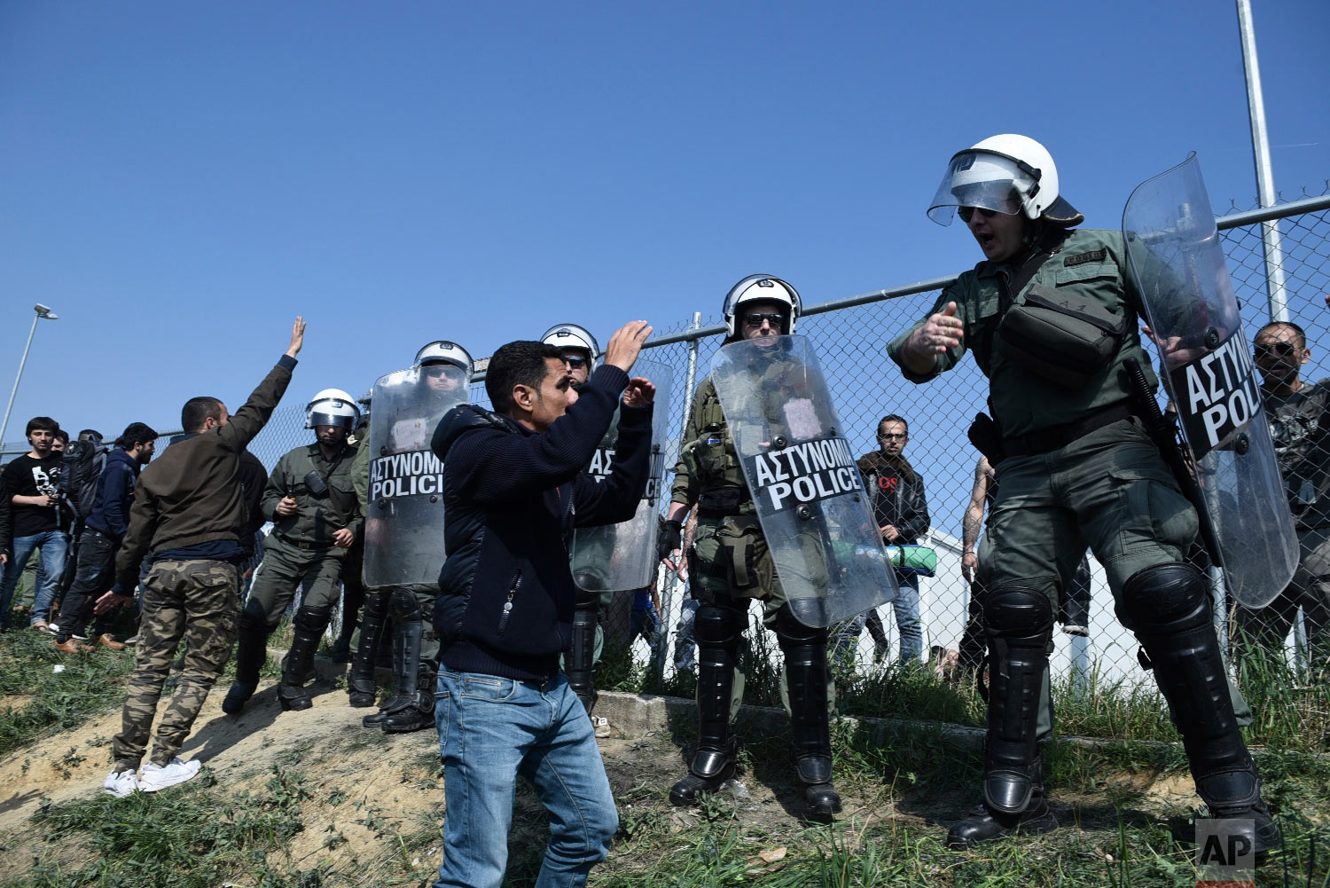 Protesting migrants gather as riot police guard a refugee camp in the village of Diavata, west of Thessaloniki, northern Greece, Thursday, April 4, 2019. (AP Photo/Giannis Papanikos)