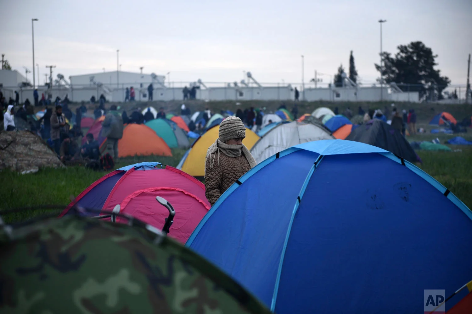 A girl stands next to a tent outside a refugee camp in the village of Diavata, west of Thessaloniki, northern Greece, Friday, April 5, 2019. (AP Photo/Giannis Papanikos)