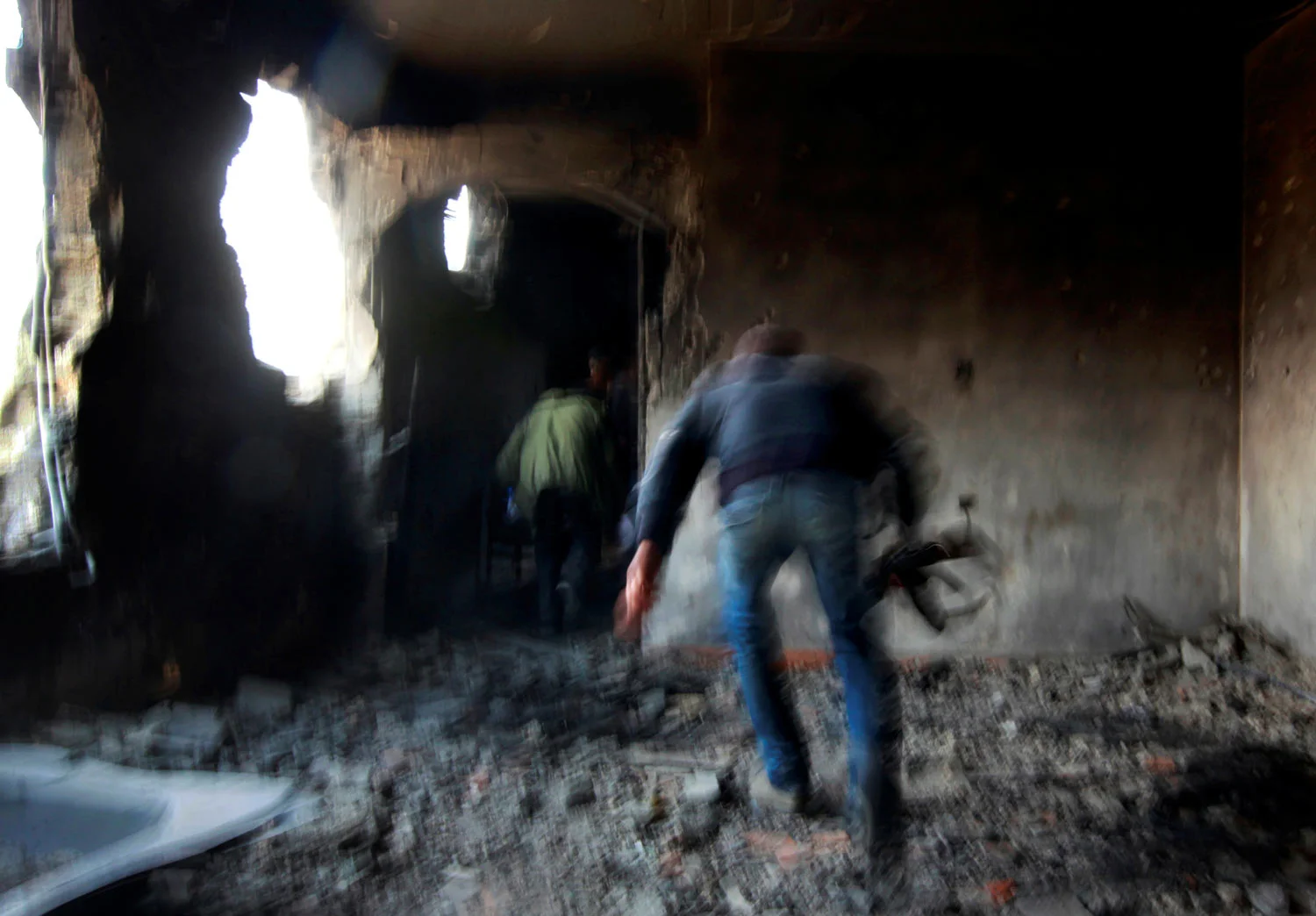 Rebel fighters run for cover inside a building on the frontline in Tripoli street in central Misrata, April 21, 2011. Tripoli street is the scene of some of the heaviest fighting between rebels and Gaddafi forces. (REUTERS/Yannis Behrakis)