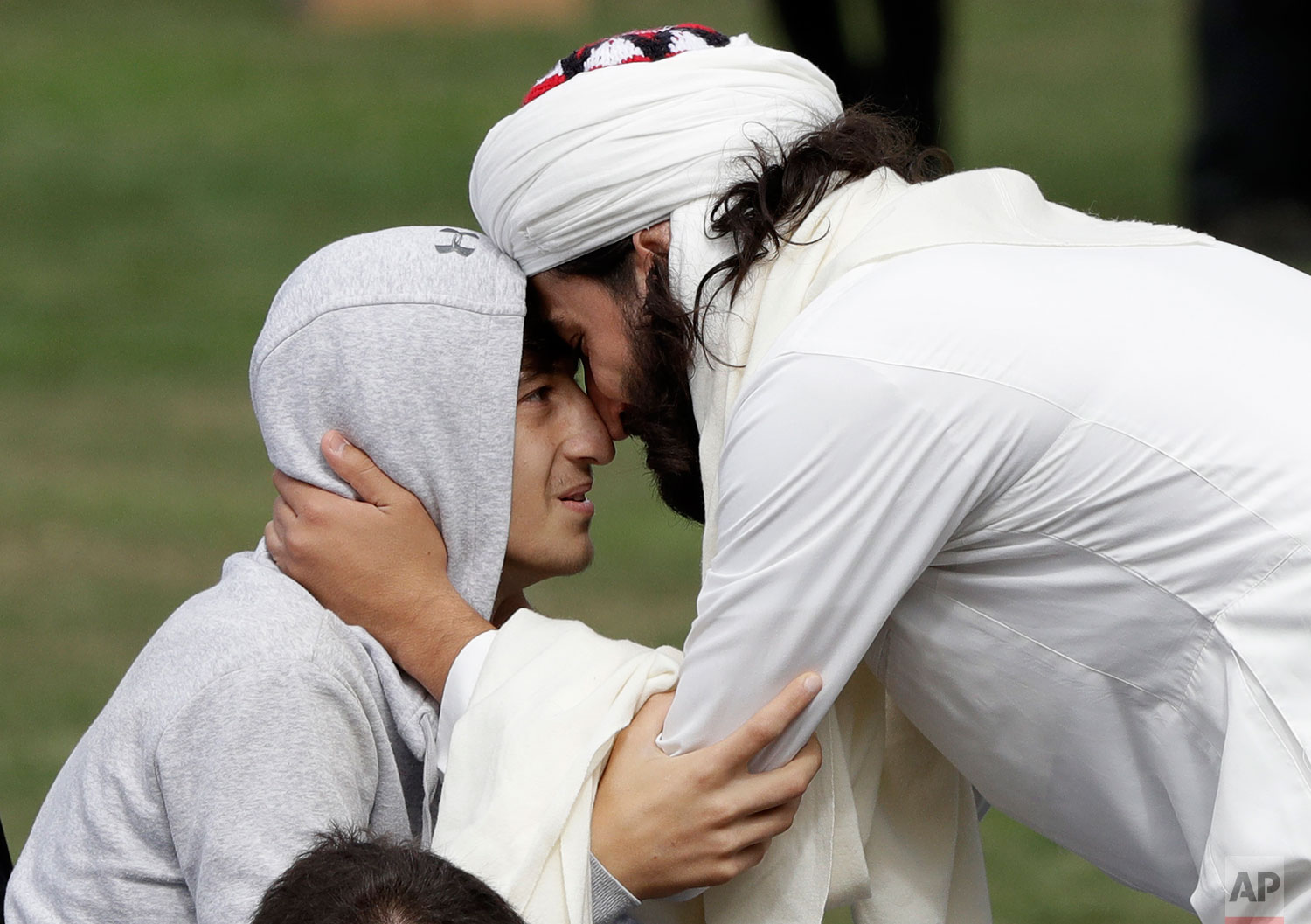 Zaid Mustafa, son and brother of victims from last week's mosque shootings is welcomed to Friday prayers at Hagley Park in Christchurch, New Zealand, Friday, March 22, 2019. Thousands of people gathered in a Christchurch city park near the Al Noor mosque where a gunman killed some of the 50 worshippers in a white supremacist attack on two mosques. (AP Photo/Mark Baker)