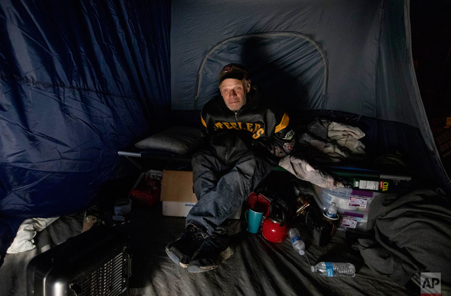 James Huebner sits in his tent in the backyard of a home where he's living with his son and brother after becoming homeless from Hurricane Michael in Youngstown, Fla, Wednesday, Jan. 23, 2019. Huebner has never been homeless before and says they can't find any affordable available housing in the area where they need to remain because of his brother's job at a nearby Walmart store. (AP Photo/David Goldman)