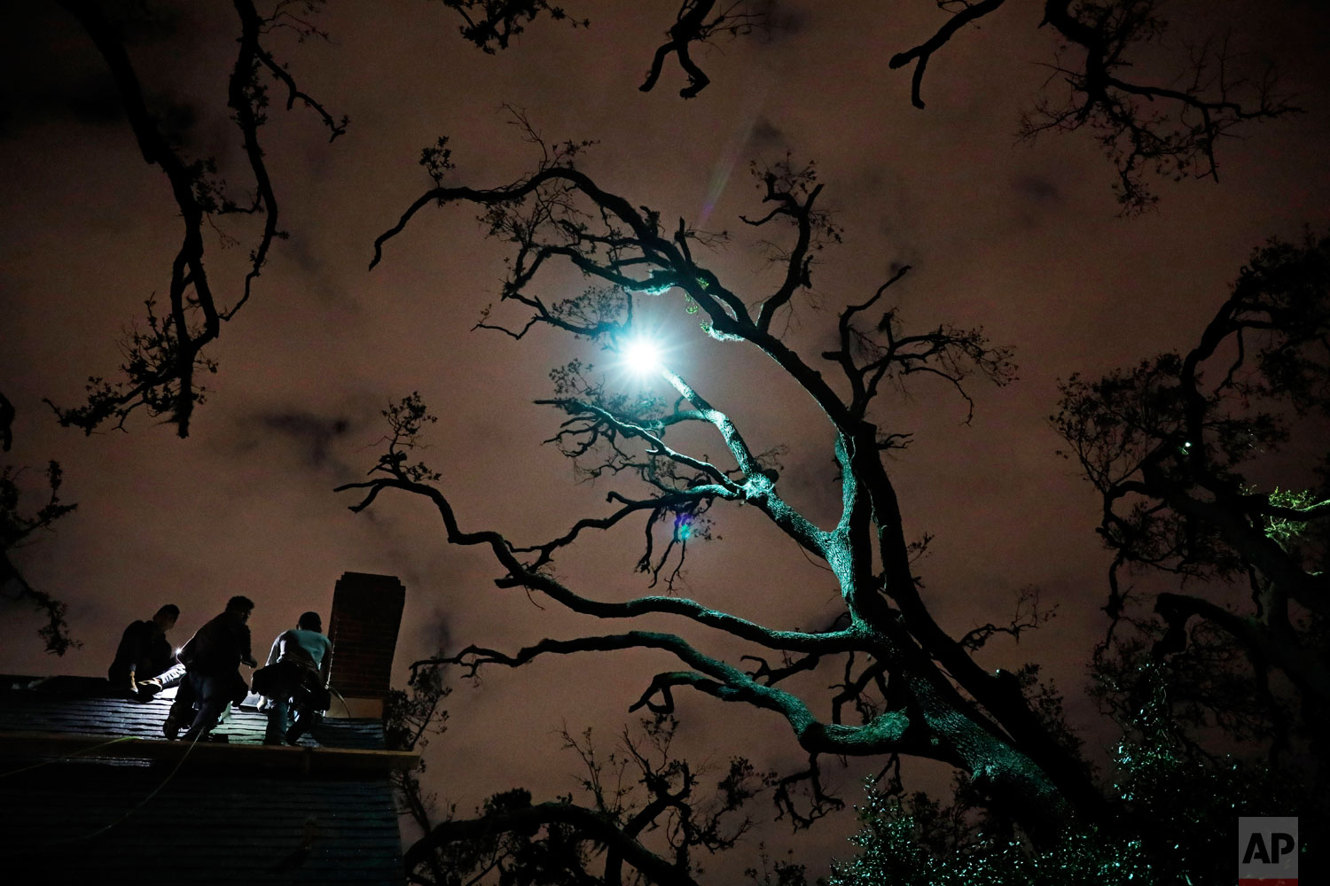  Workers repair a roof at night under trees left bare by Hurricane Michael in Panama City, Fla, Tuesday, Jan. 22, 2019. Some residents have been able to make their homes livable again with cosmetic repairs. Others simply left town: The county's stude
