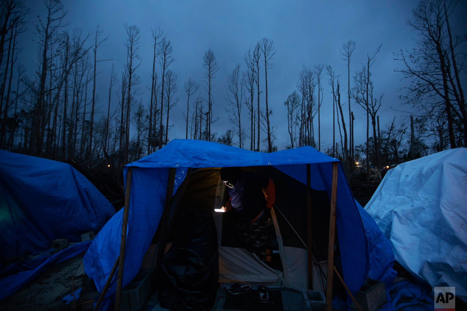 Jacinta Wheeler checks her phone in the entryway of her tent in the backyard of a home where she's living after becoming homeless from Hurricane Michael in Youngstown, Fla, Wednesday, Jan. 23, 2019. Wheeler, whose apartment was damaged by the hurricane, has been working construction jobs and helping make repairs to neighbors' properties while she stays in her tent.
"Everybody wants the American dream," the Trinidad native said. "If this is the dream, I don't want it." (AP Photo/David Goldman)