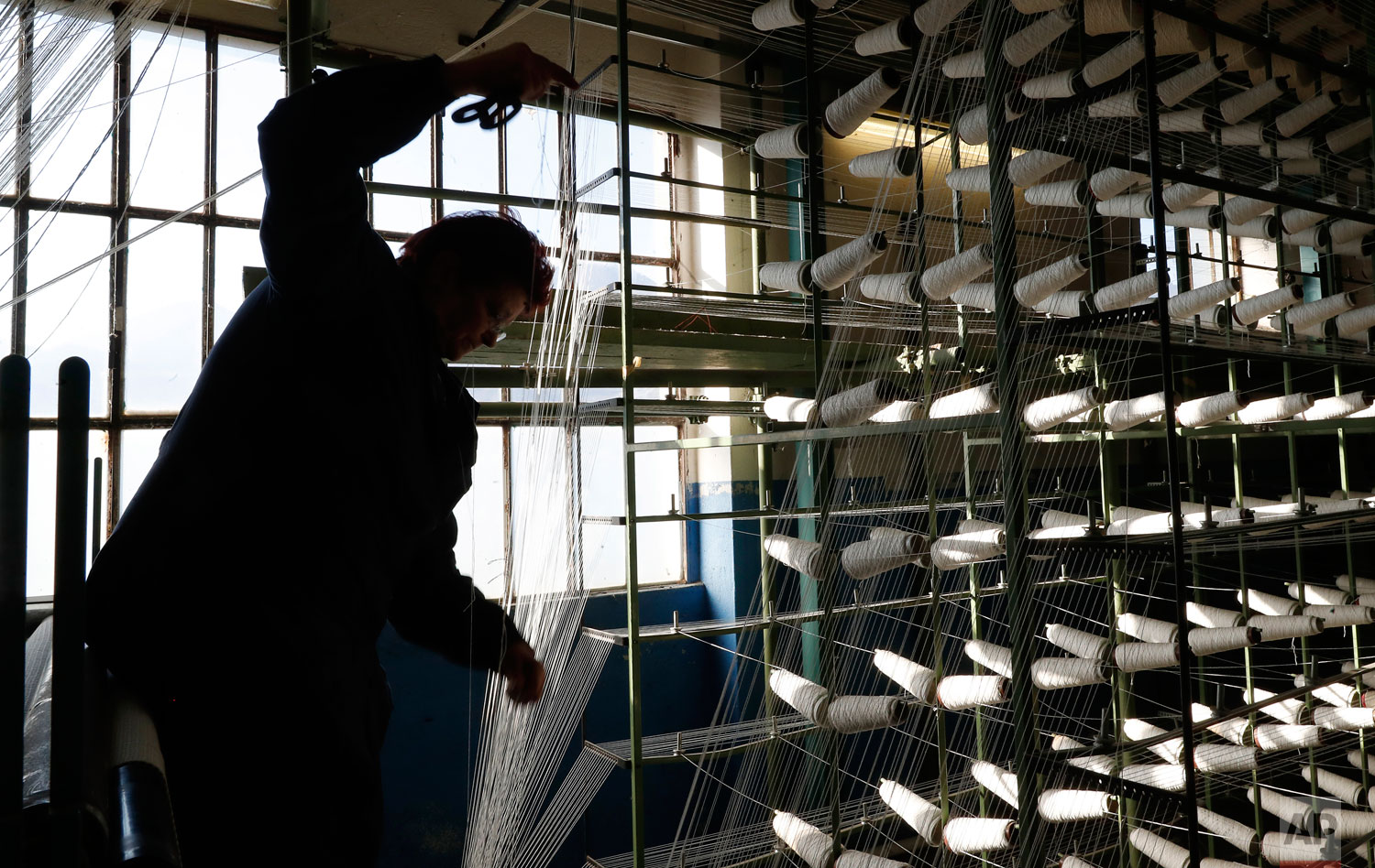 In this photo taken on Wednesday, Feb. 6, 2019, a woman works at "La Rete" (The Net) factory in Monte Isola, Lake Iseo, northern Italy. Step off the ferry onto Monte Isola and it feels like going back in time. The factory of La Rete S.r.l. , an old-fashioned producer of nets for soccer goals, is indeed a throwback. Workers still use their hands to weave the nets that have been used at World Cups stretching back to the 1990 tournament in Italy, throughout Serie A and in recent Champions League finals, too. There used to be several net producers on Monte Isola but La Rete is the last company still running. “Historically, this is a territory where nets have been made. It started with fishing and hunting then was slowly transformed into nets for sports,” said Elio Agnesi, who along with partner (and Monte Isola mayor) Fiorello Turla, has been running the company for 40 years. Monte Isola is a picturesque island located in the middle of Lake Iseo in northern Italy. All of the company’s 18 workers and reside on the island and use scooters to reach the factory each day on narrow paths. (AP Photo/Antonio Calanni)