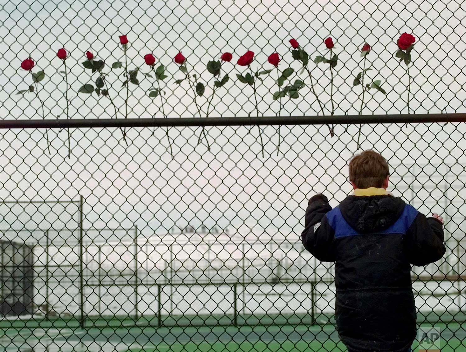  A boy looks through the fence at the Columbine High School tennis courts in Littleton, Colo., Saturday, April 24, 1999. Thirteen roses were placed on the fence in remembrance of the 13 people killed by two gun wielding students at the school, Tuesda