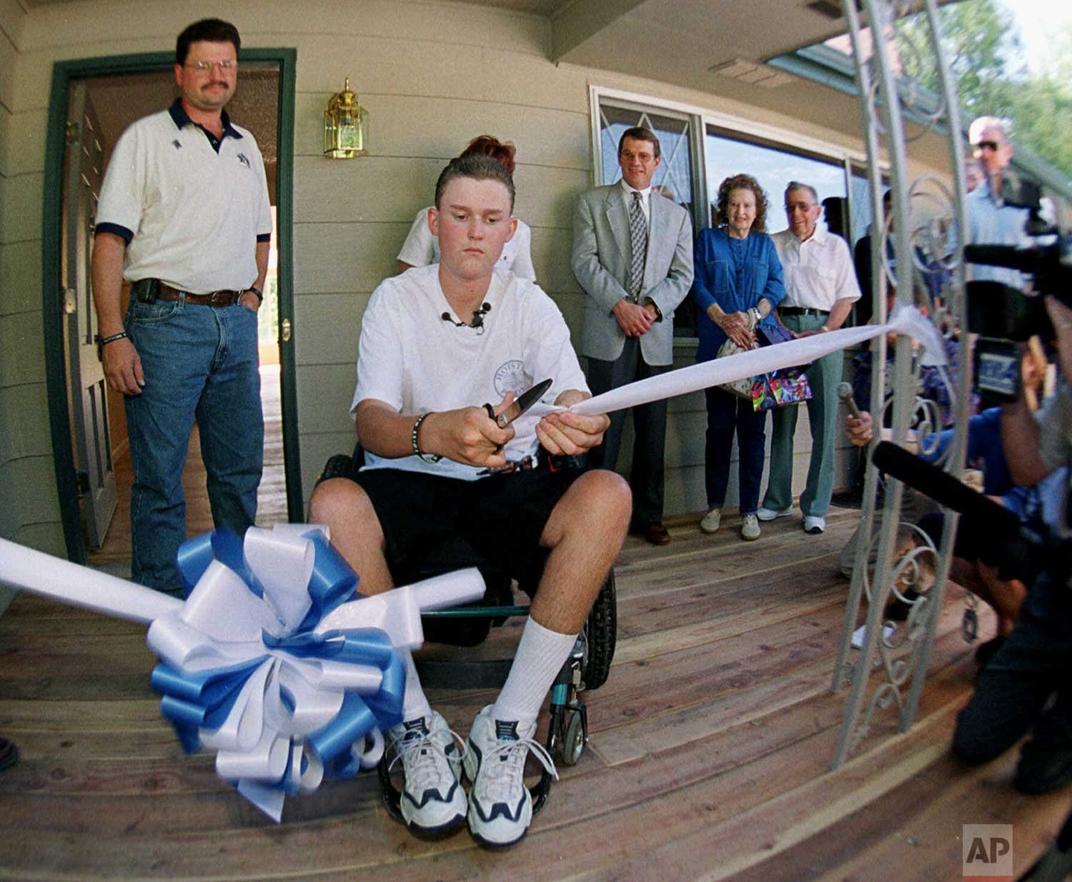  Columbine High School shooting victim Sean Graves, center, cuts the ribbon to welcome reporters and photographers into his parents' home that has been modified to be accessible to wheelchairs early Thursday, Aug. 26, 1999, in the southwest Denver su