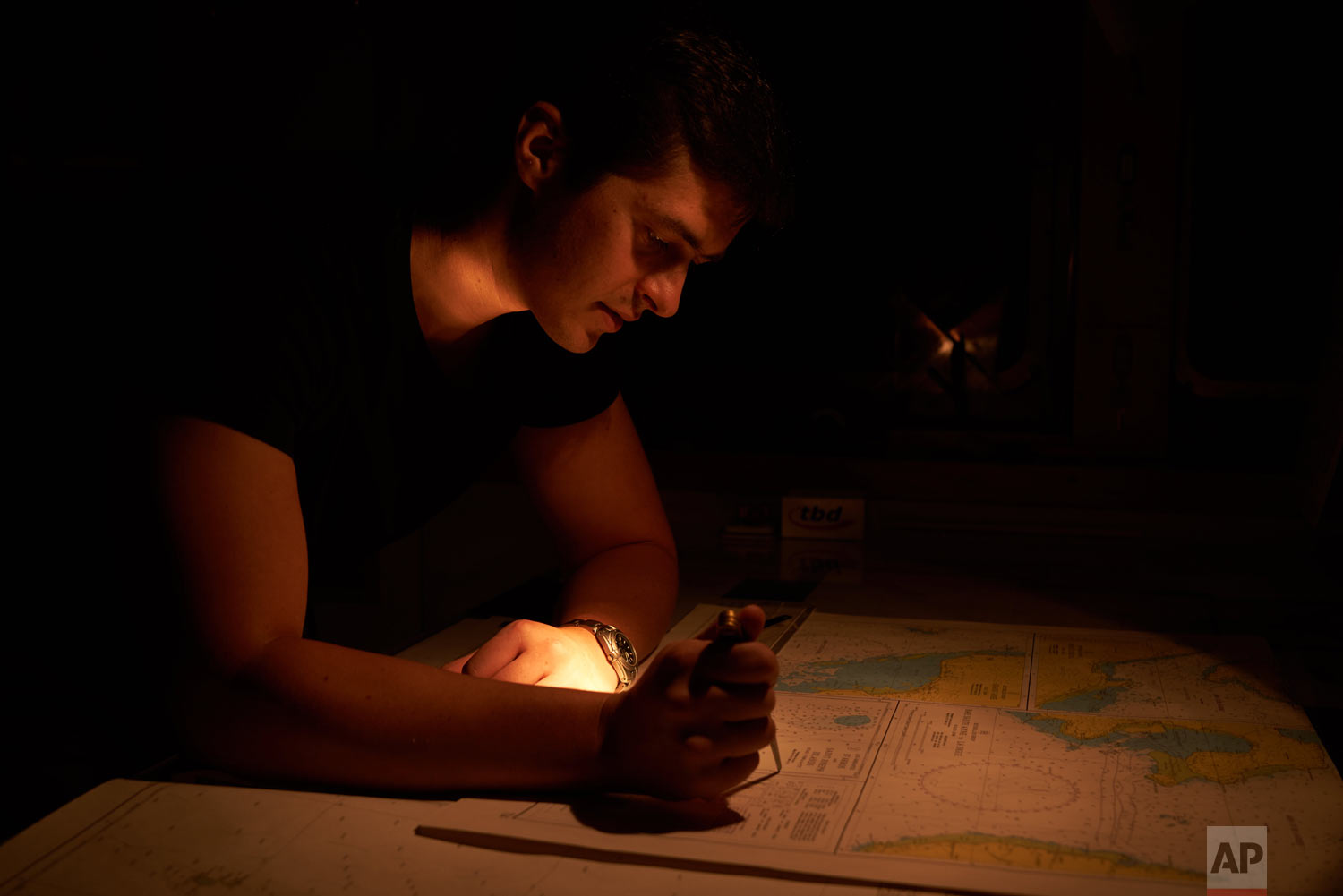Second officer Konstantin Afanasjev studies the chart of St. Joseph island in the Seychelles during his night watch on board the Ocean Zephyr, April 11, 2019. (AP Photo/David Keyton)